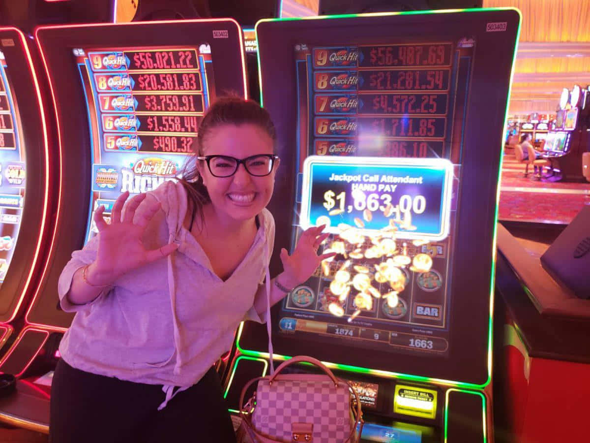 game 桌布 壁紙 — 一位戴眼鏡的女士微笑著在燈光明亮的賭場老虎機前慶祝贏得1663美元的大獎。
