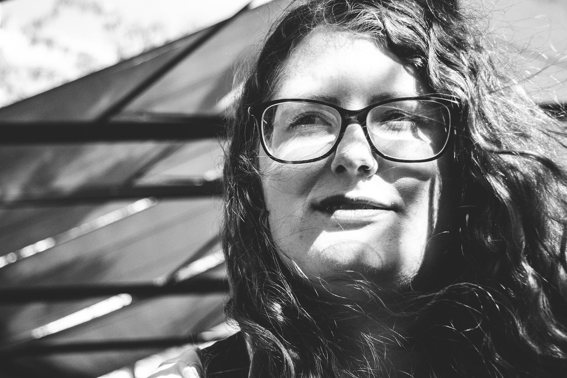 Woman 桌布 壁紙 — 一位戴眼鏡的女性在明亮陽光下向上微笑的黑白肖像。