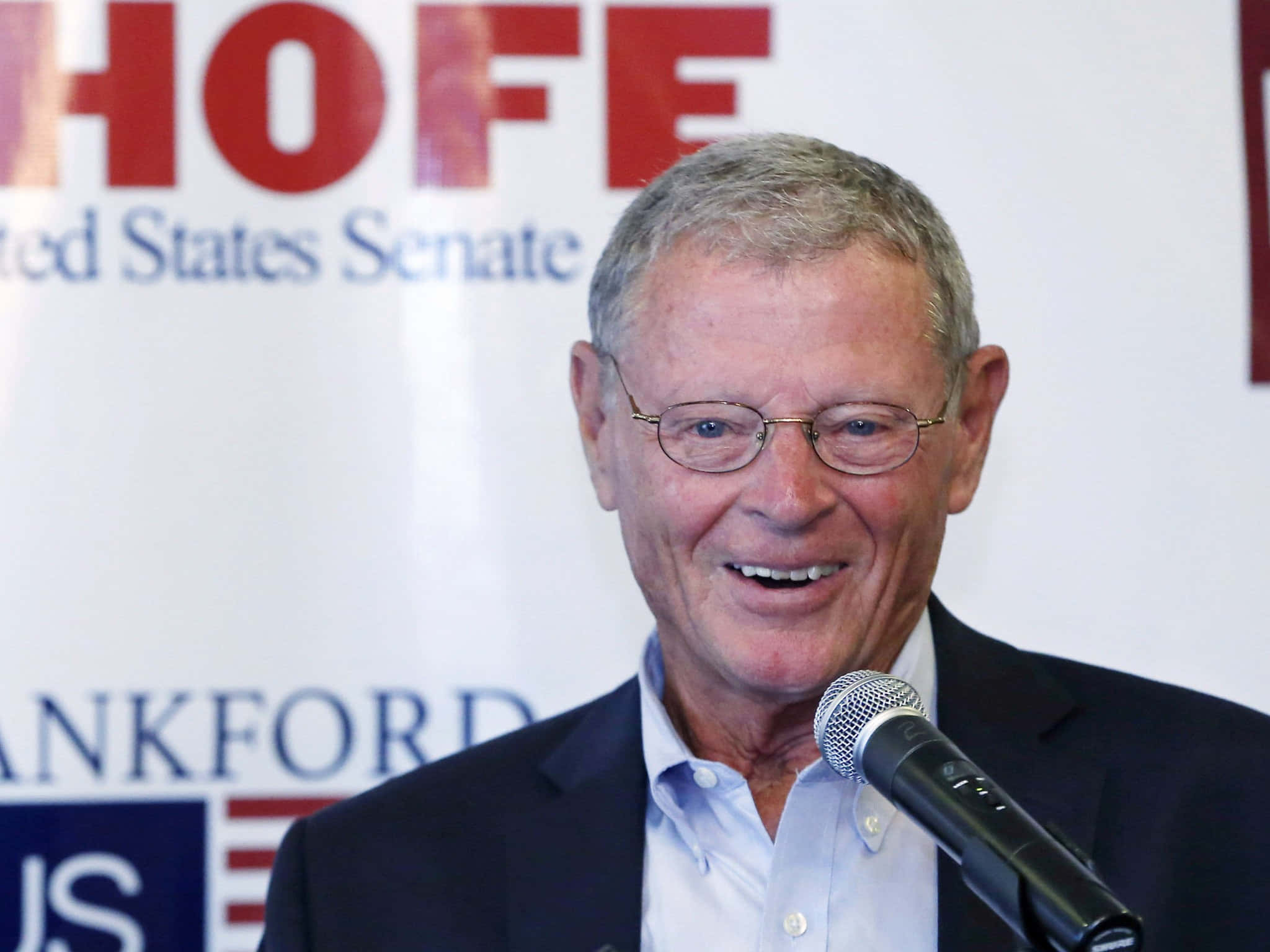 Celebrity 桌布 壁紙 — 一位戴眼鏡的微笑長者，在帶有 'HOFF United States Senate' 背景的競選活動中對著麥克風發言。