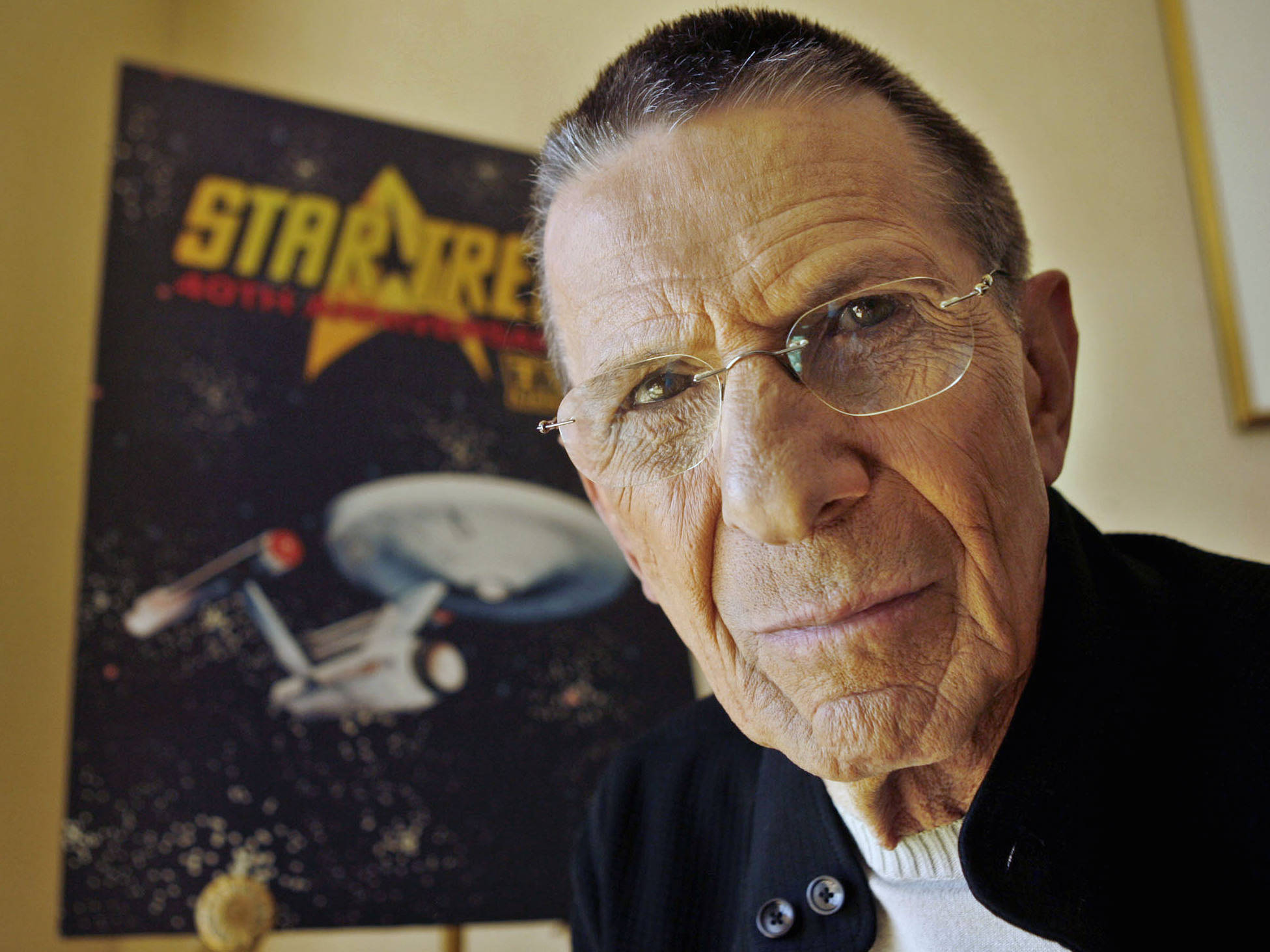 Spock 桌布 壁紙 — 一位戴眼鏡的長者凝視著鏡頭，身後是《星際爭霸戰》海報。