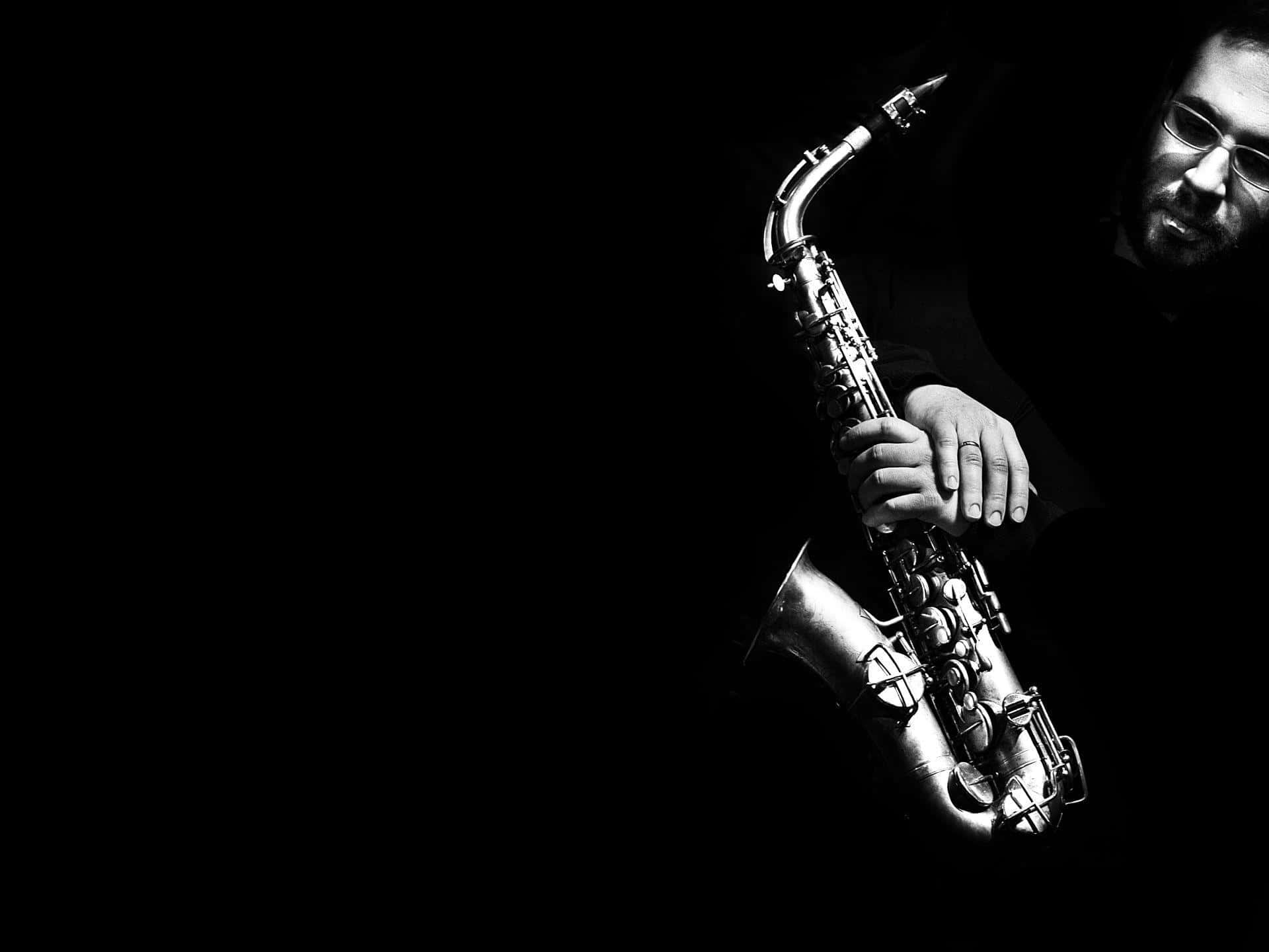 Jazz 桌布 壁紙 — 一位戴眼鏡的音樂家在黑色背景前，於戲劇性的聚光燈下拿著薩克斯風。