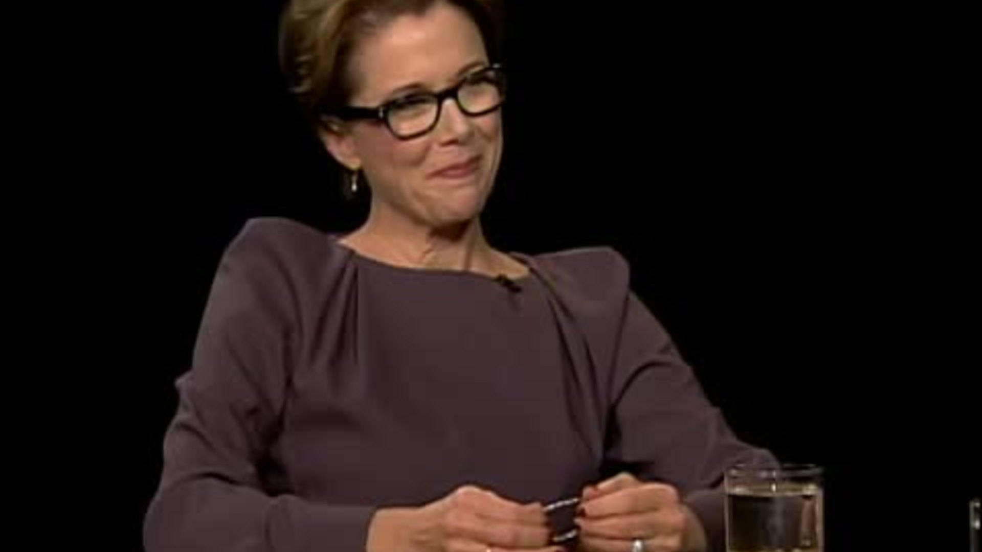Celebrity 桌布 壁紙 — 一位戴眼鏡短髮的女性坐在黑色背景前微笑，手持一個小物件。
