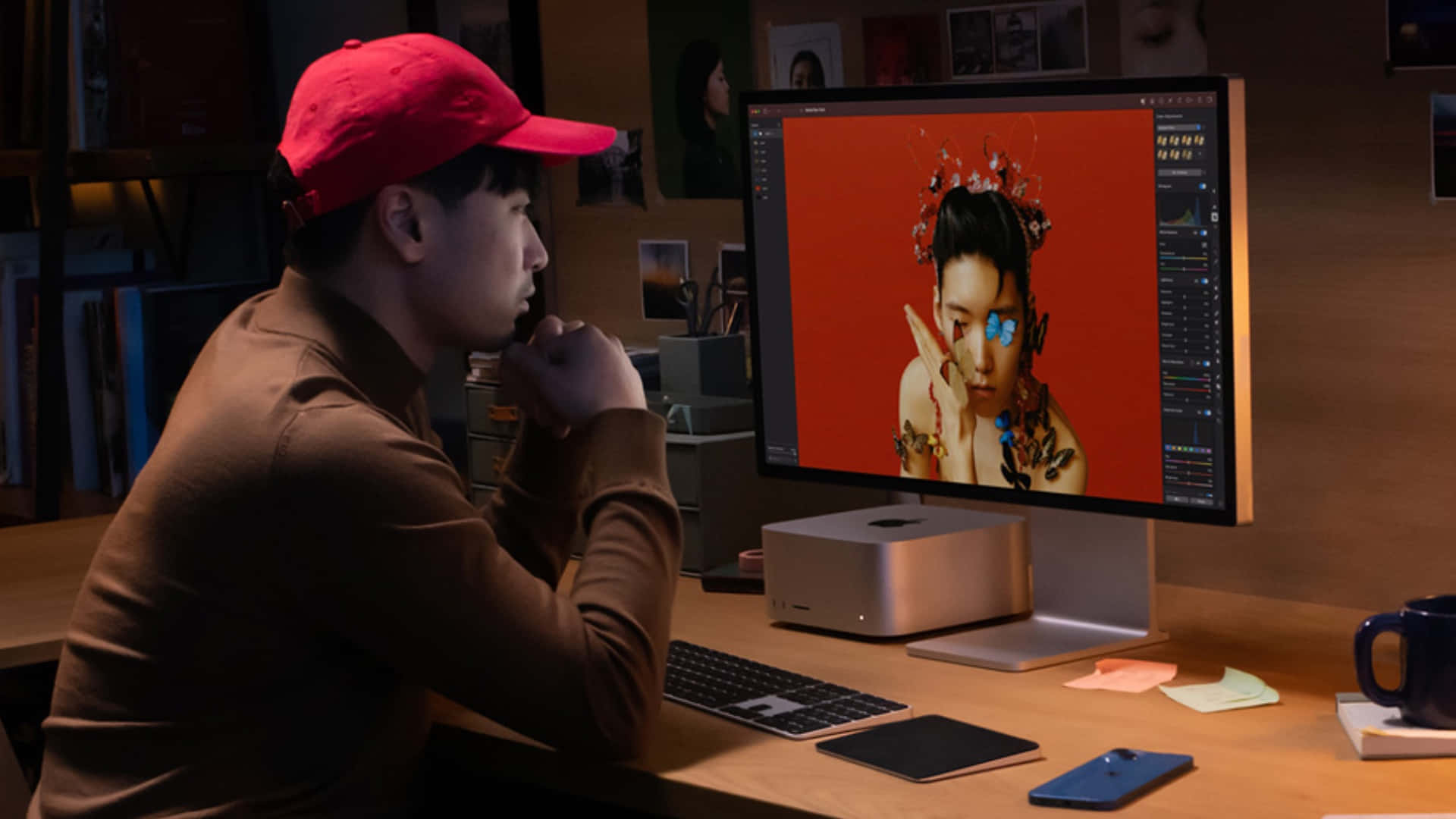 Mac 桌布 壁紙 — 一位戴紅帽的設計師正在發光的顯示器上專注地創作一個帶有花卉裝飾的人物數位肖像。