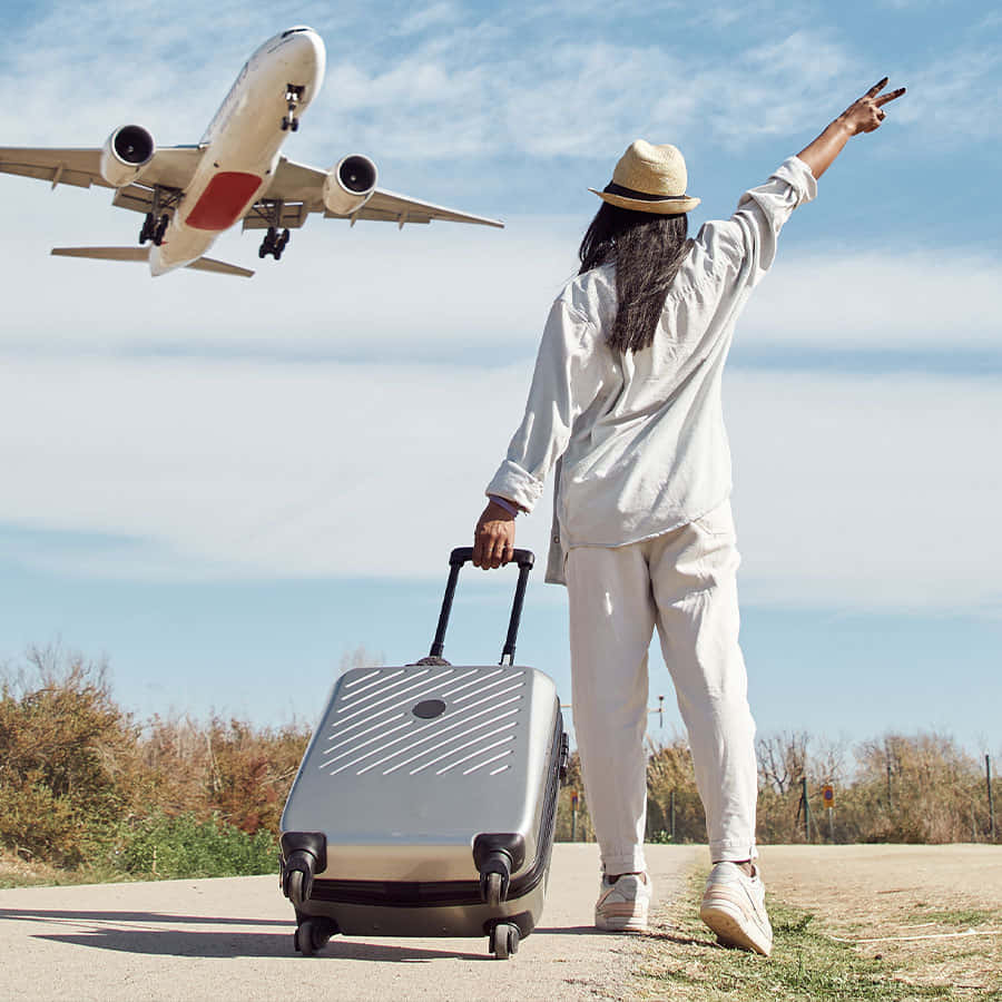 Travel Desktop 桌布 壁紙 — 一位戴草帽的旅客揮手告別，一架大型飛機在明亮的藍天中飛過頭頂。