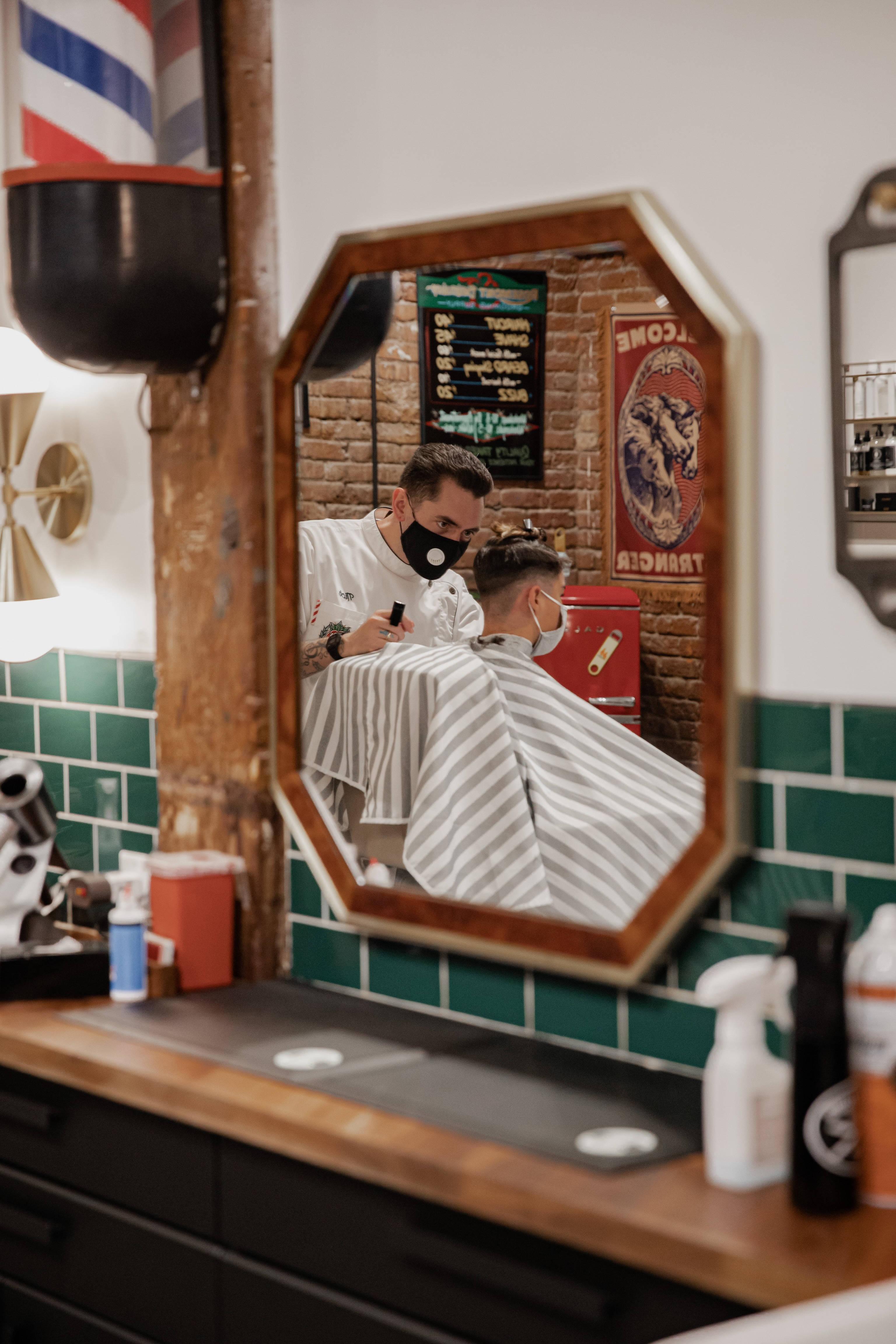 Haircut 桌布 壁紙 — 一位戴著口罩的理髮師在鋪有綠色瓷磚和條紋柱的復古理髮店為客人修剪頭髮。