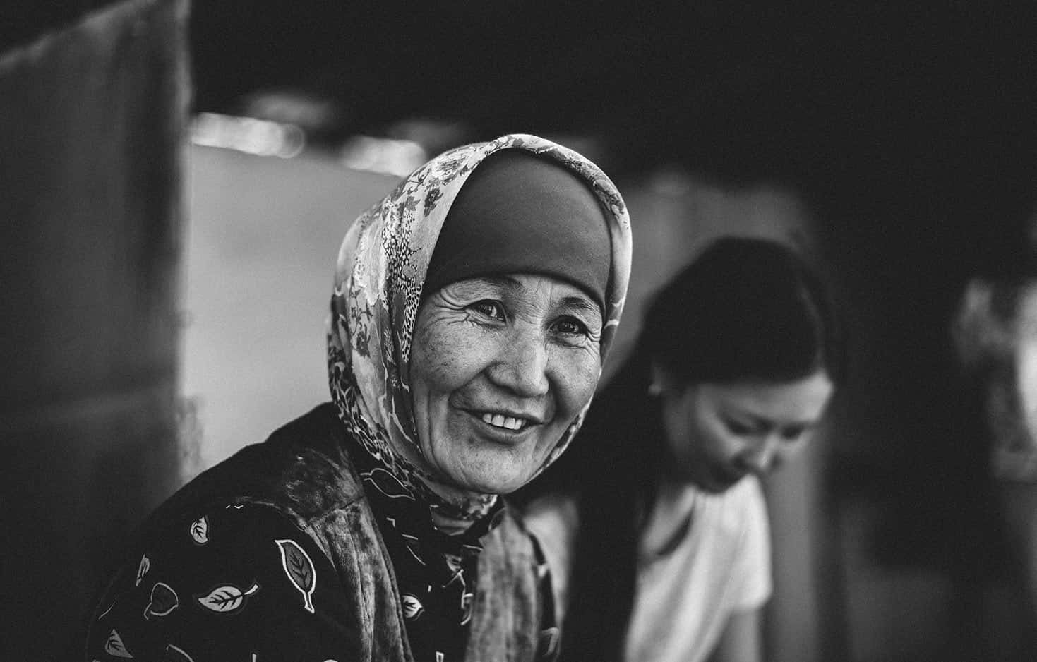 Meaningful 桌布 壁紙 — 一位戴著圖案頭巾的快樂老年女性在柔和模糊的室內環境中溫暖地微笑。