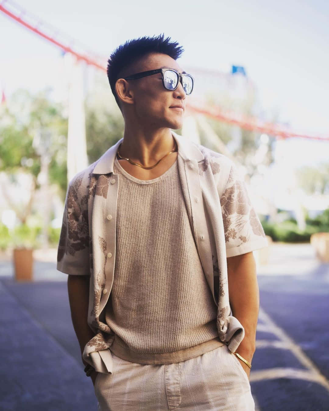 Mens Fashion 桌布 壁紙 — 一位戴著太陽眼鏡和圖案襯衫的時尚男士在明亮的陽光下自信地站在戶外。