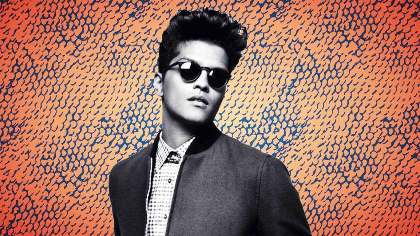 Bruno Mars 桌布 壁紙 — 一位戴著太陽眼鏡和外套的時尚男士站在充滿活力的橙色和藍色圖案背景前。
