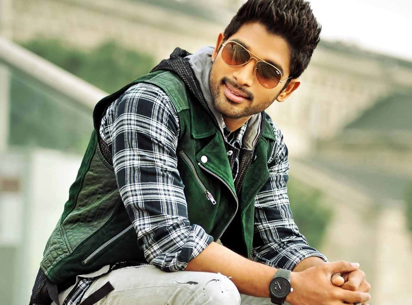 Allu Arjun 桌布 壁紙 — 一位戴著太陽眼鏡和格子襯衫的時尚男士，在模糊的城市背景下自信地在戶外擺姿勢。
