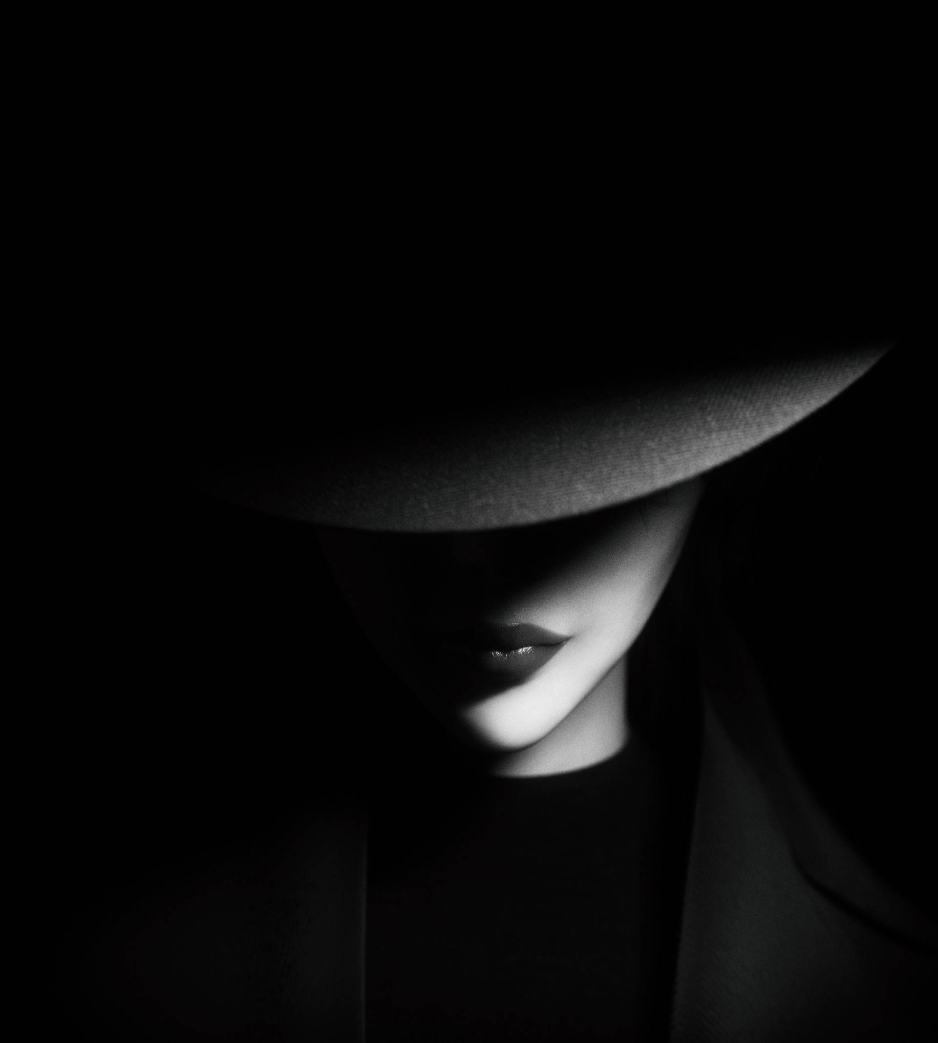 shadow 桌布 壁紙 — 一位戴著寬邊帽子的女性，在鮮明的黑白肖像中，臉上投下深深的陰影。