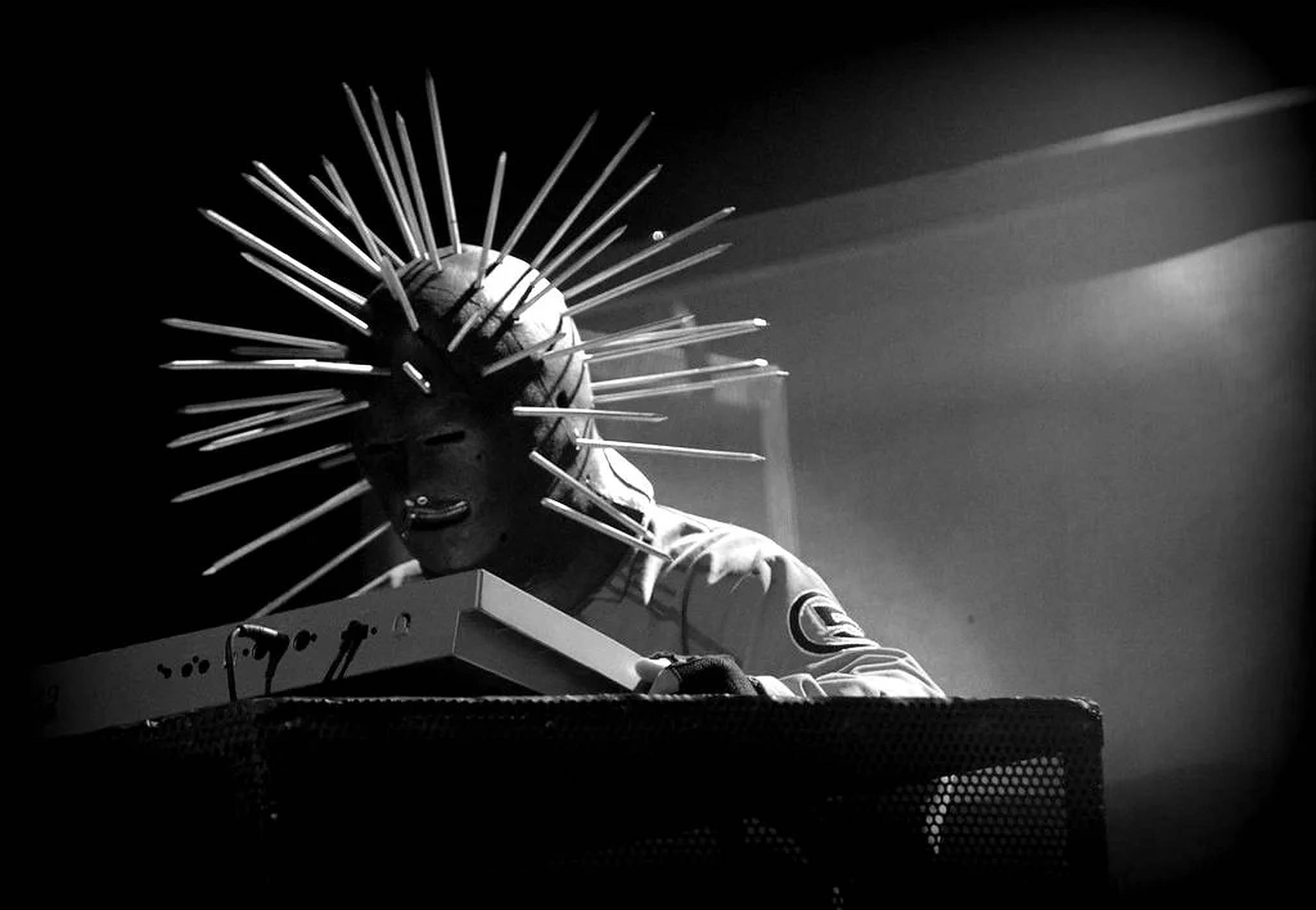 craig jones 桌布 壁紙 — 一位戴著尖刺頭盔的音樂家在黑白戲劇性舞台燈光下彈奏鍵盤。