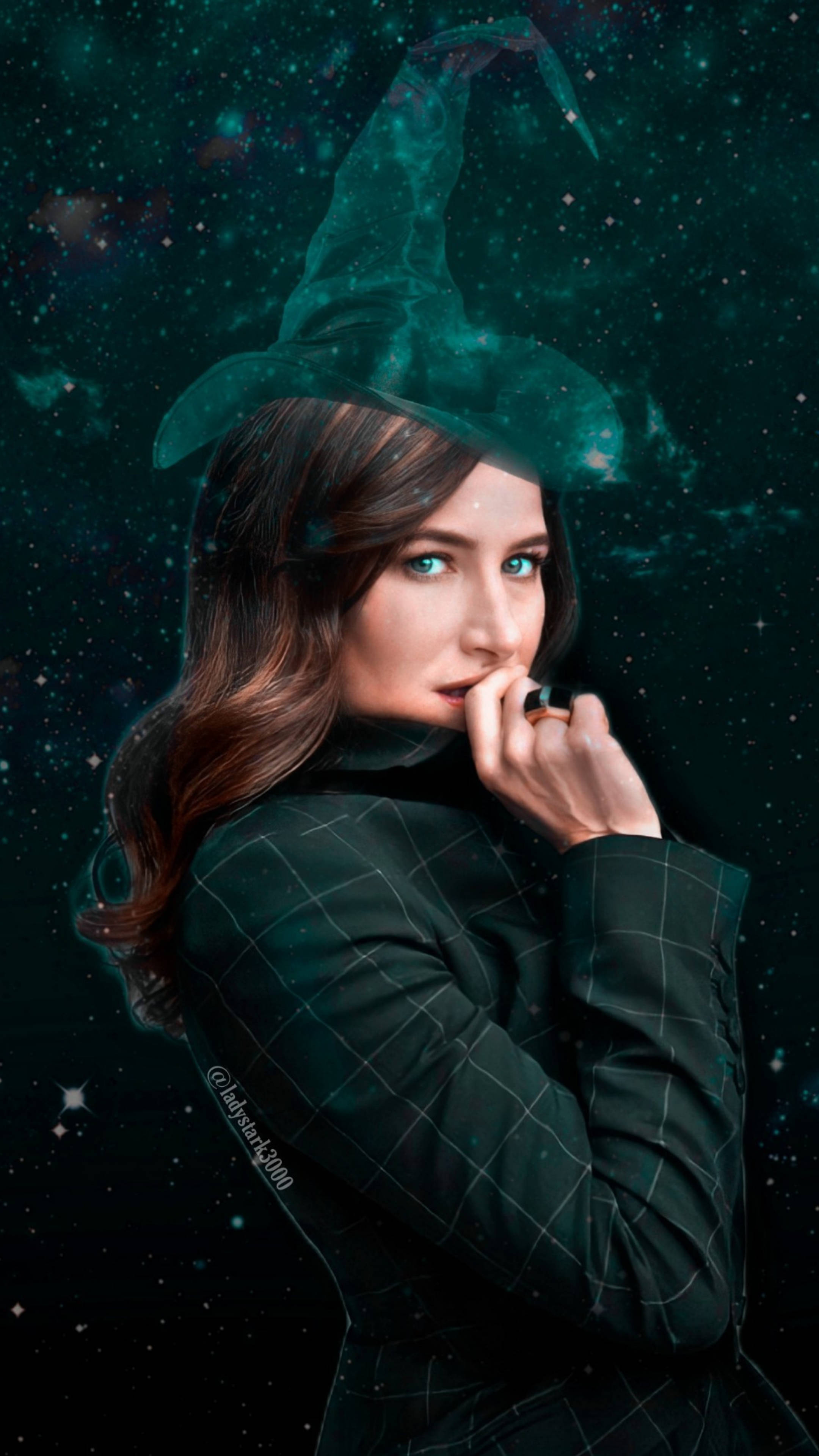 Agatha 桌布 壁紙 — 一位戴著巫師帽和格子外套的女性站在星光燦爛的宇宙背景下，周圍有發光的青綠色星雲。