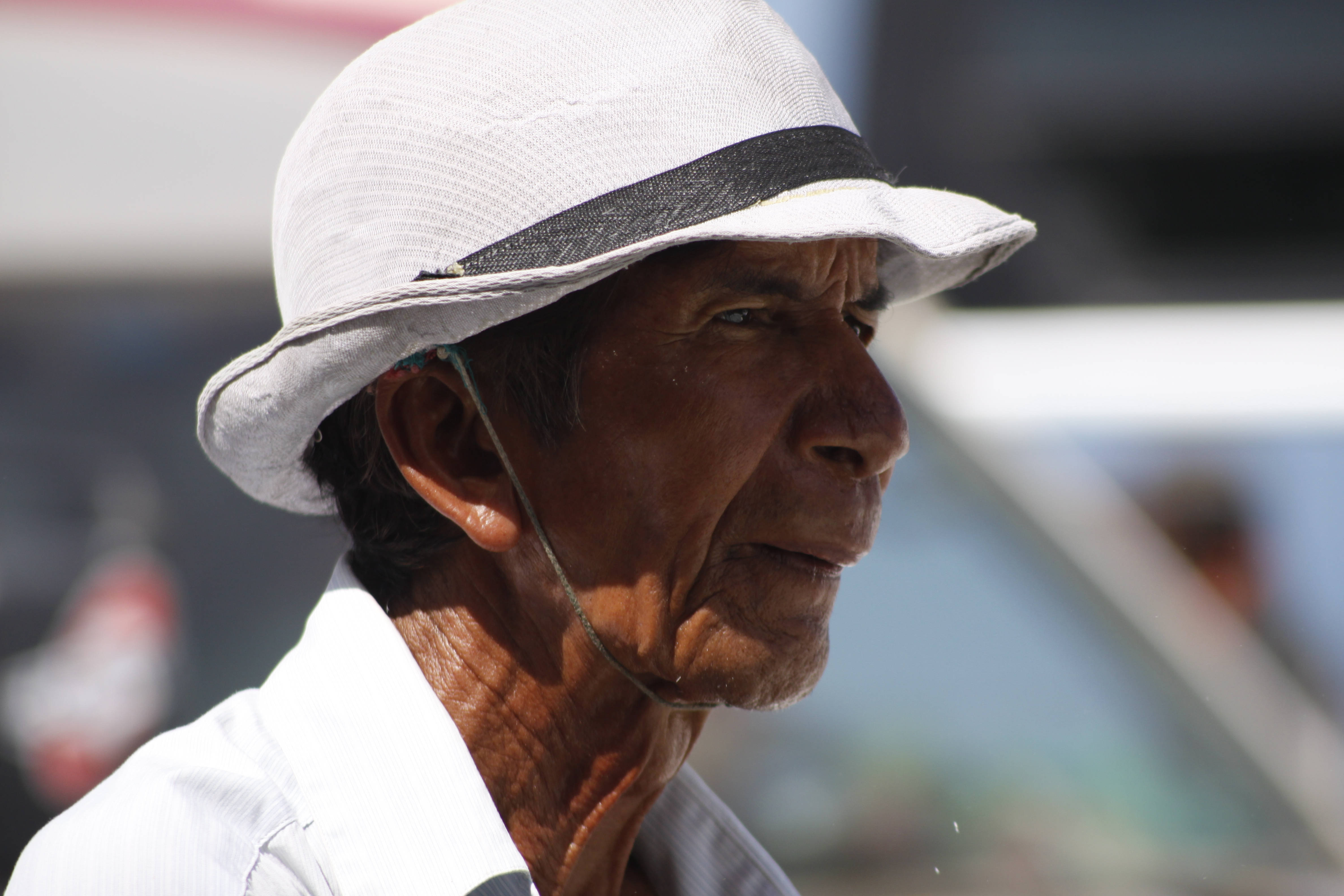 Cambodia 桌布 壁紙 — 一位戴著帶黑色帶子的白色太陽帽的長者特寫肖像，在明亮的陽光下若有所思地凝視戶外。