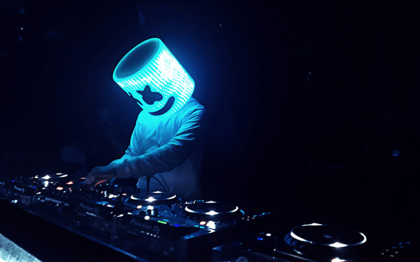 Marshmallow Dj 桌布 壁紙 — 一位戴著發光藍色棉花糖頭盔的DJ在昏暗的舞台燈光下於唱盤上混音。
