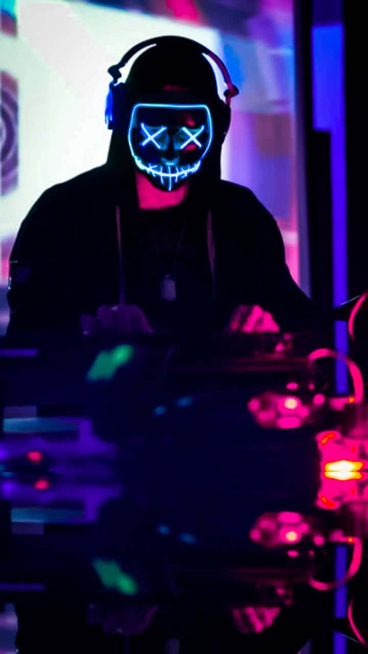 Neon Mask 桌布 壁紙 — 一位戴著發光霓虹面具和耳機的DJ，在夜店的紫色和粉紅色燈光下表演。