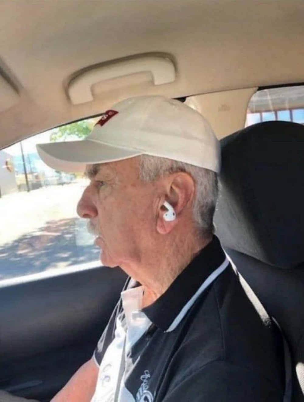 Earphone 桌布 壁紙 — 一位戴著白色帽子和耳塞的年長男性坐在汽車駕駛座上向前看。