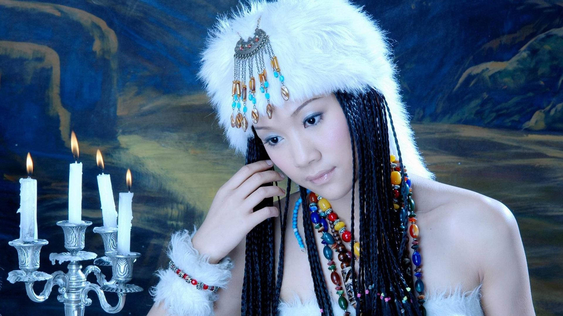 美麗高畫質 桌布 壁紙 — 一位戴著白色毛帽和彩色珠子的女人，在點燃的燭台旁，對著繪製的山景背景溫柔地凝視。