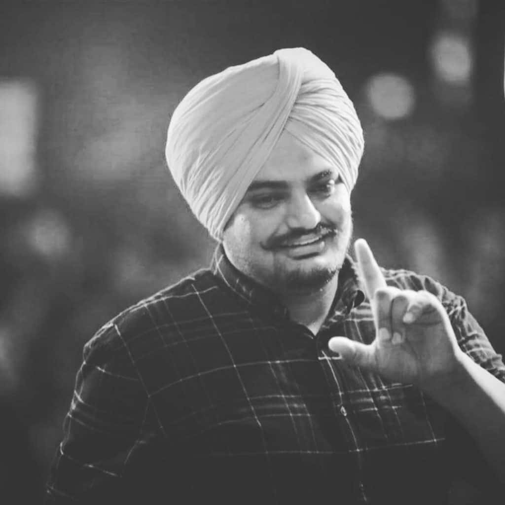戴頭巾的男子微笑並做出和平手勢 — Sidhu Moose Wala 壁紙
