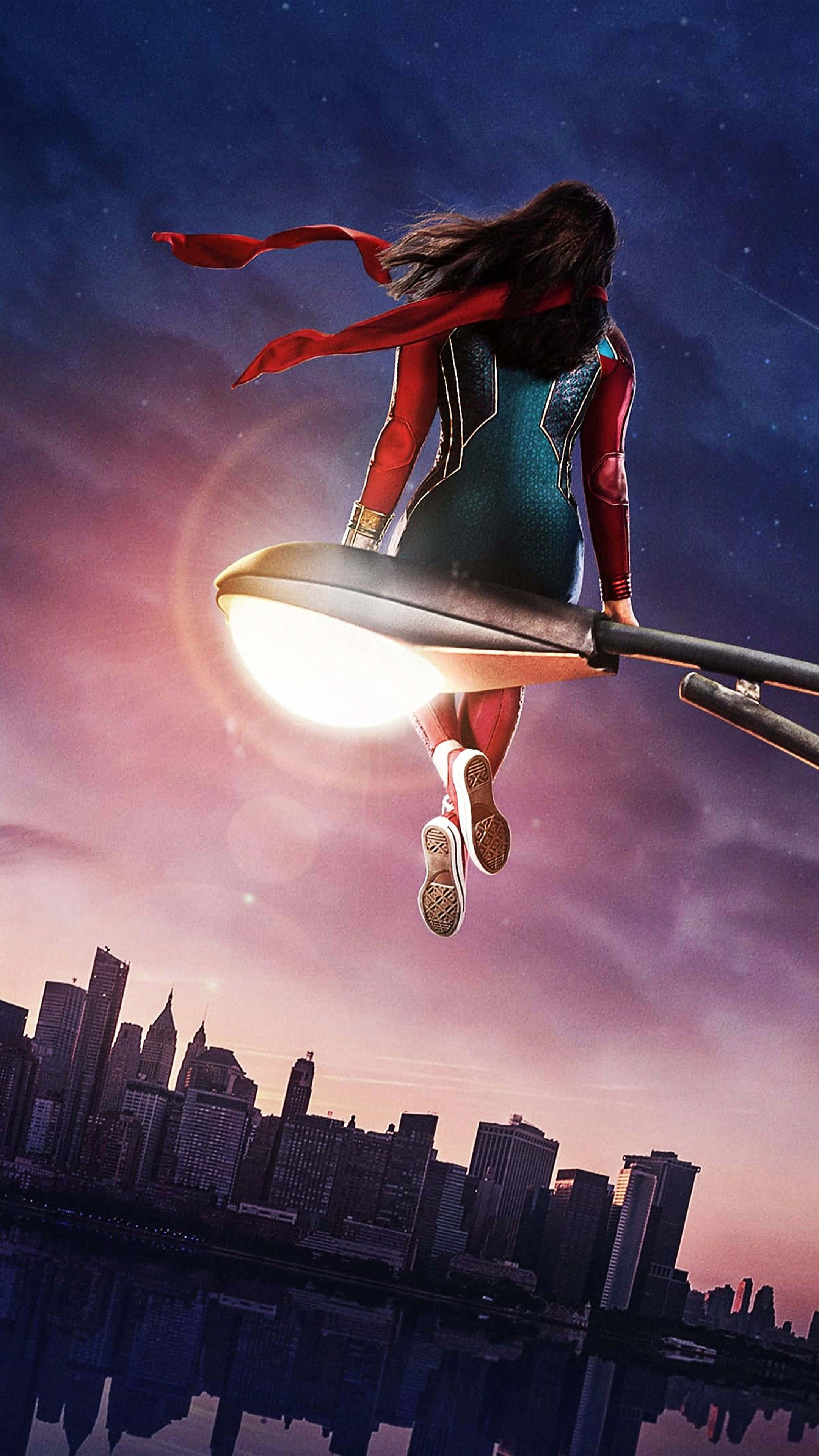 4K Marvel's Avengers 桌布 壁紙 — 一位戴著紅色圍巾的女超級英雄在黃昏時分騎著發光路燈在城市天際線上方。