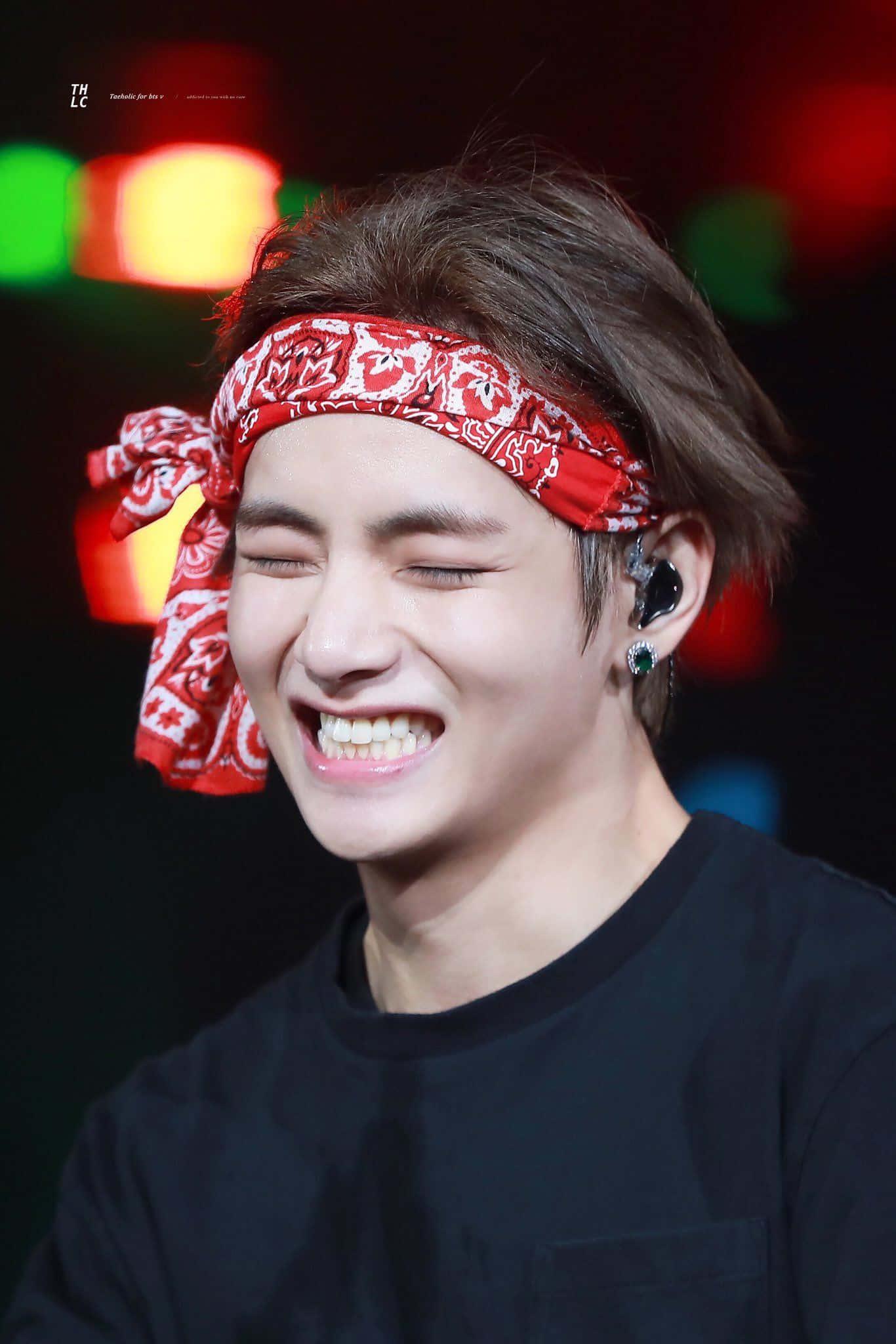 Taehyung Cute 桌布 壁紙 — 一位戴著紅色頭巾的年輕人在色彩繽紛的模糊燈光下在舞台上開懷大笑。