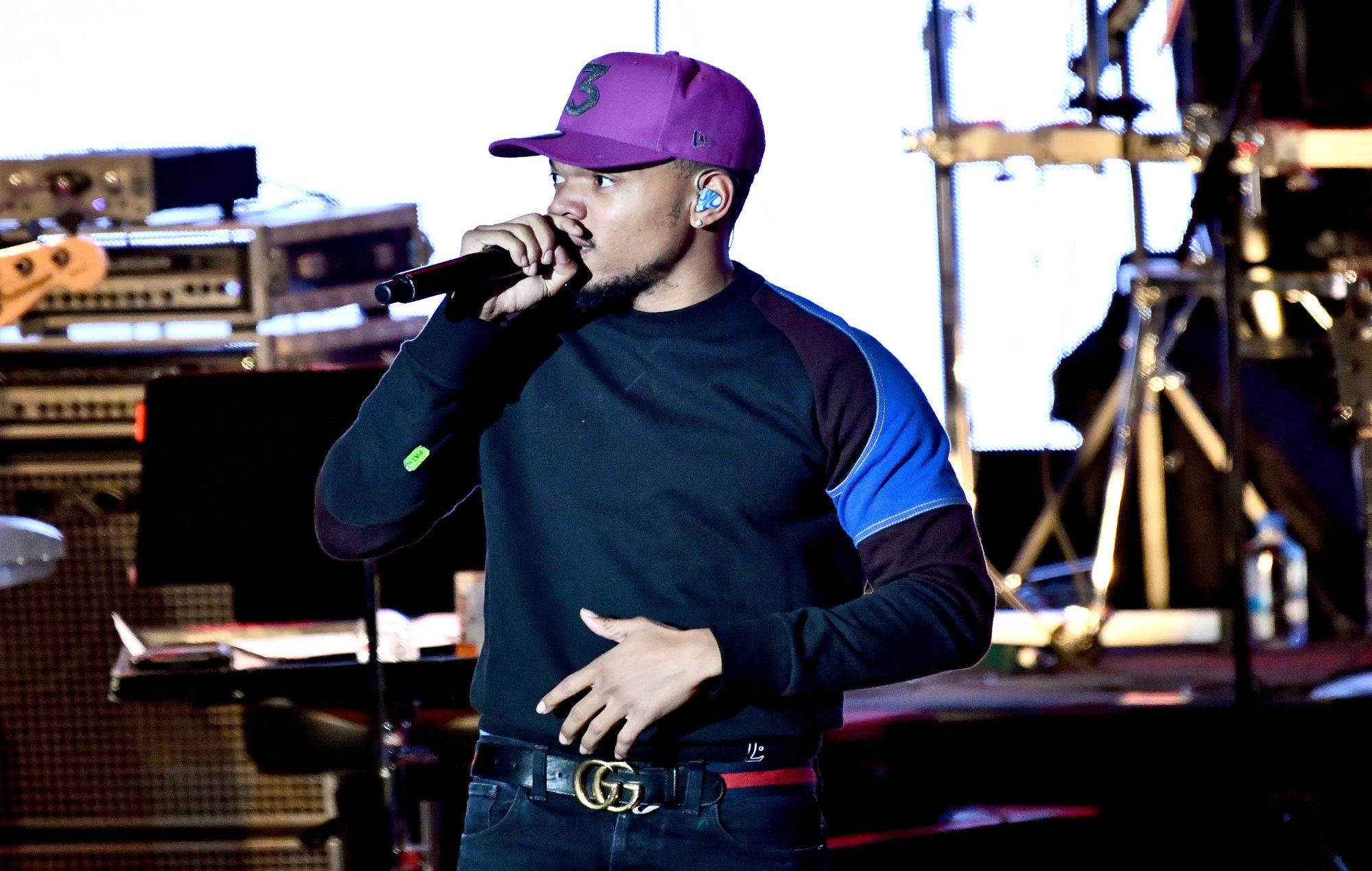 chance 桌布 壁紙 — 一位戴著紫色帽子和黑色襯衫的男性饒舌歌手在燈光明亮的舞台上對著麥克風熱情表演。