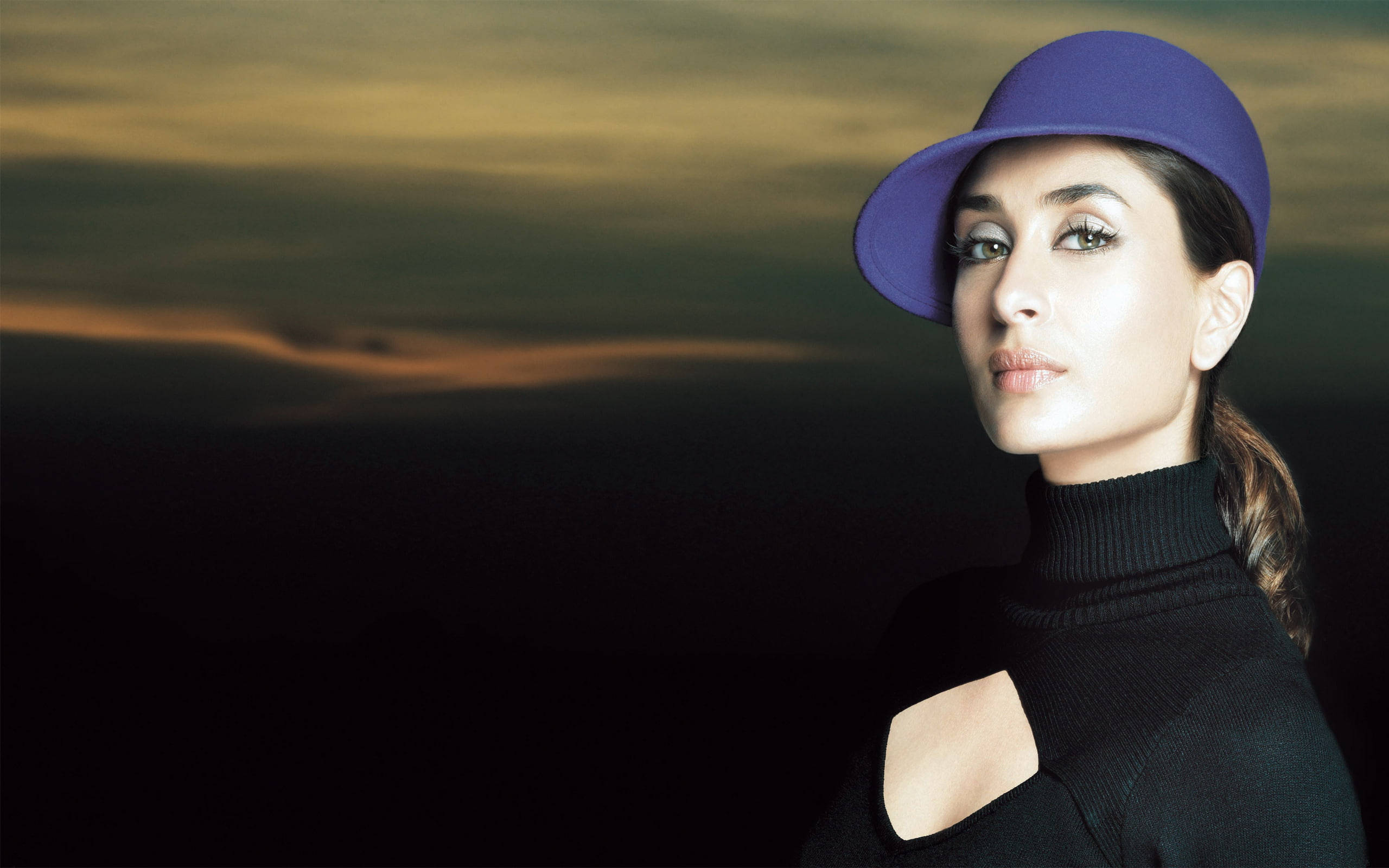 Kareena 桌布 壁紙 — 一位戴著紫色帽子和黑色高領毛衣的女性，在戲劇性的日落天空下自信地凝視。