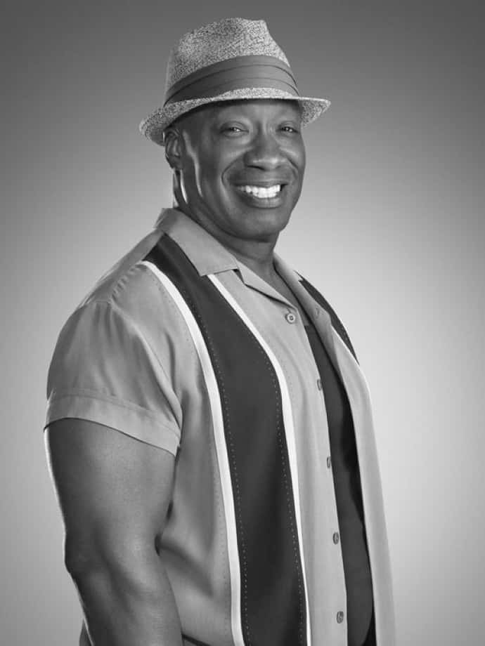 Michael Clarke Duncan 桌布 壁紙 — 一位戴著紳士帽和條紋襯衫的微笑男子，在灰色漸變背景前自信地擺姿勢，拍攝黑白工作室肖像。