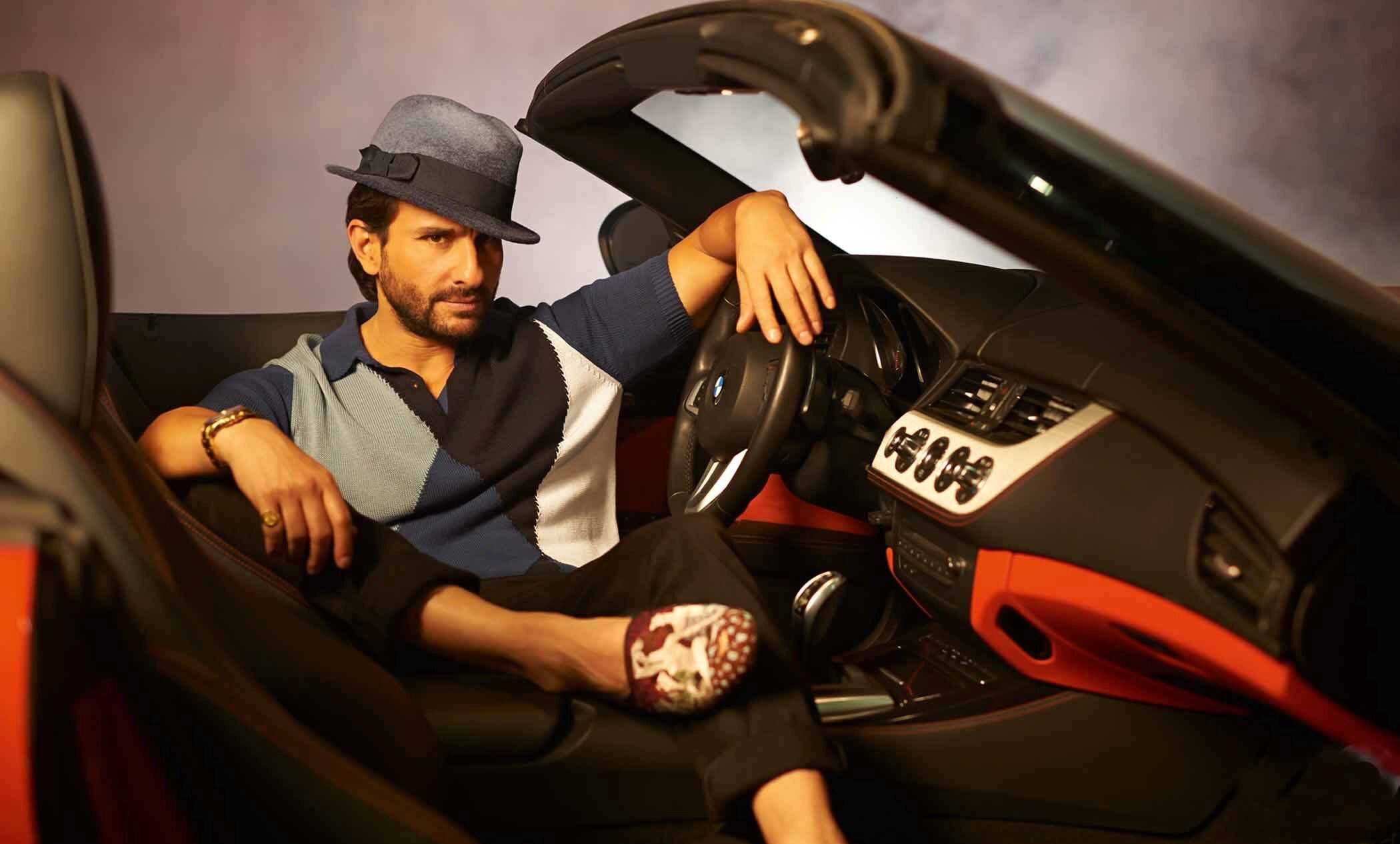 Saif Ali Khan 桌布 壁紙 — 一位戴著紳士帽的時尚男士自信地坐在一輛時尚黑橙色敞篷跑車的駕駛座上。