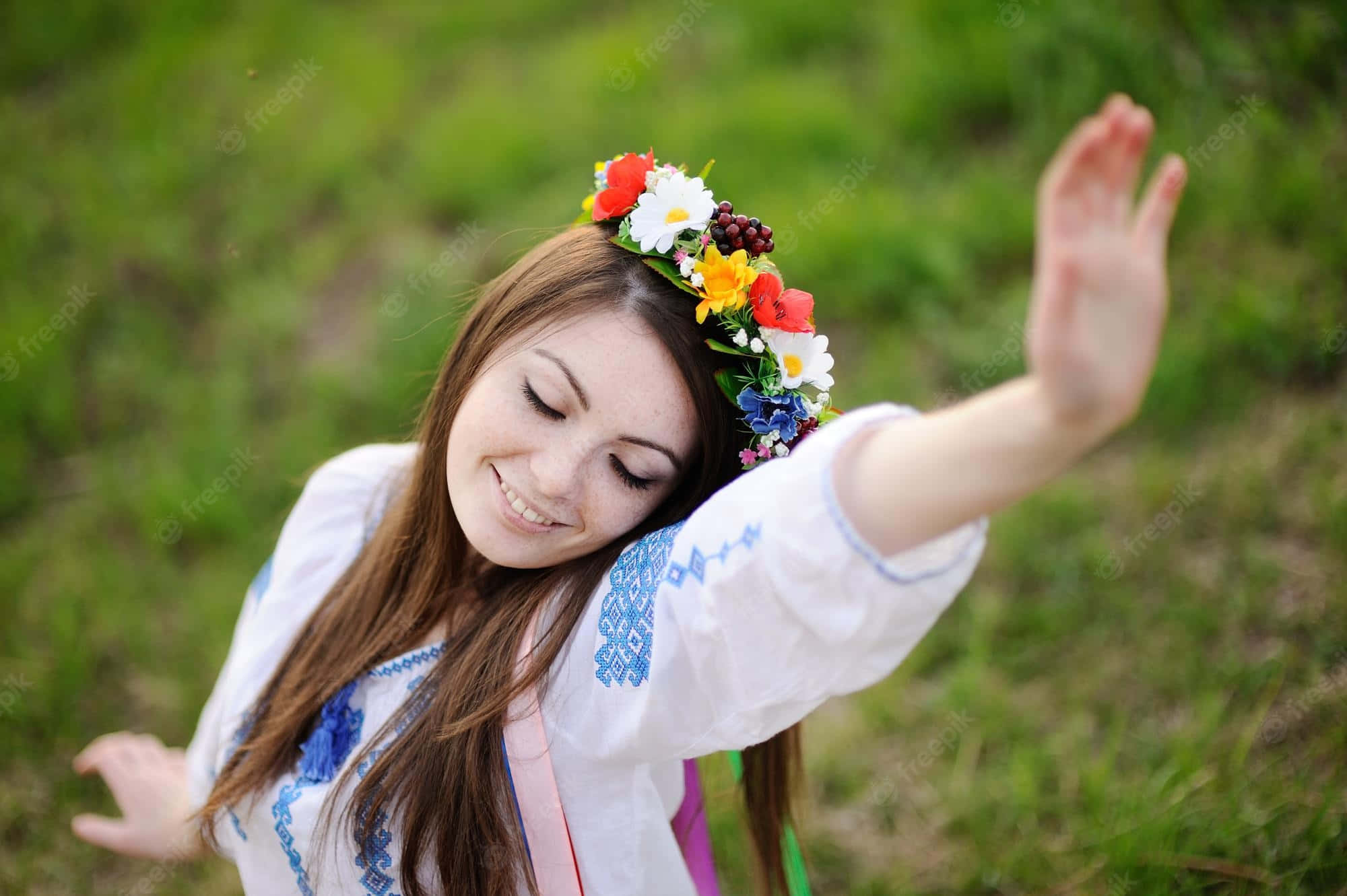 女孩 桌布 壁紙 — 一位戴著花冠和刺繡襯衫的快樂女子，閉著眼睛微笑，在陽光照耀的草地上跳舞。