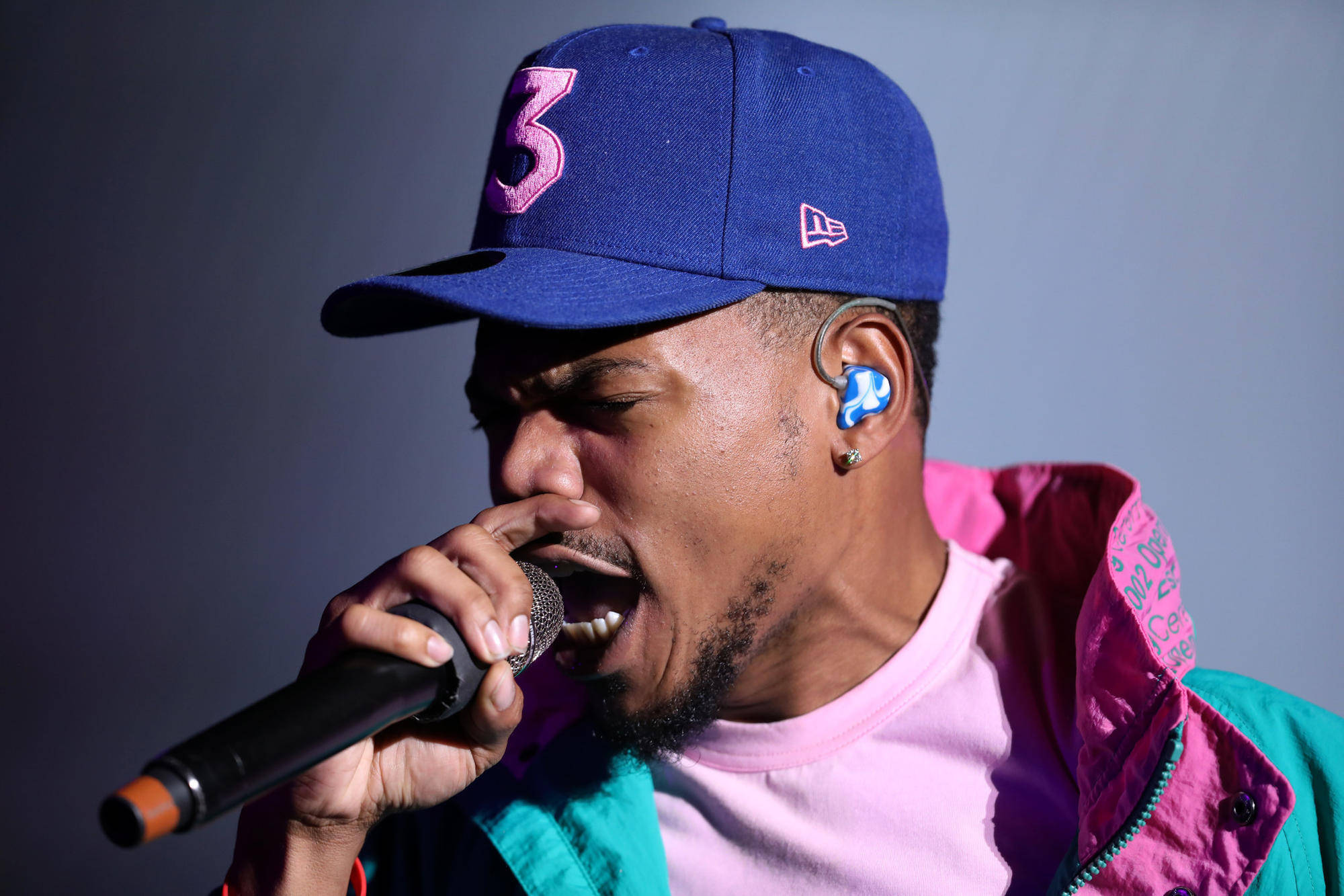 chance 桌布 壁紙 — 一位戴著藍色帽子和彩色外套的男饒舌歌手在舞台燈光下熱情地對著麥克風唱歌。