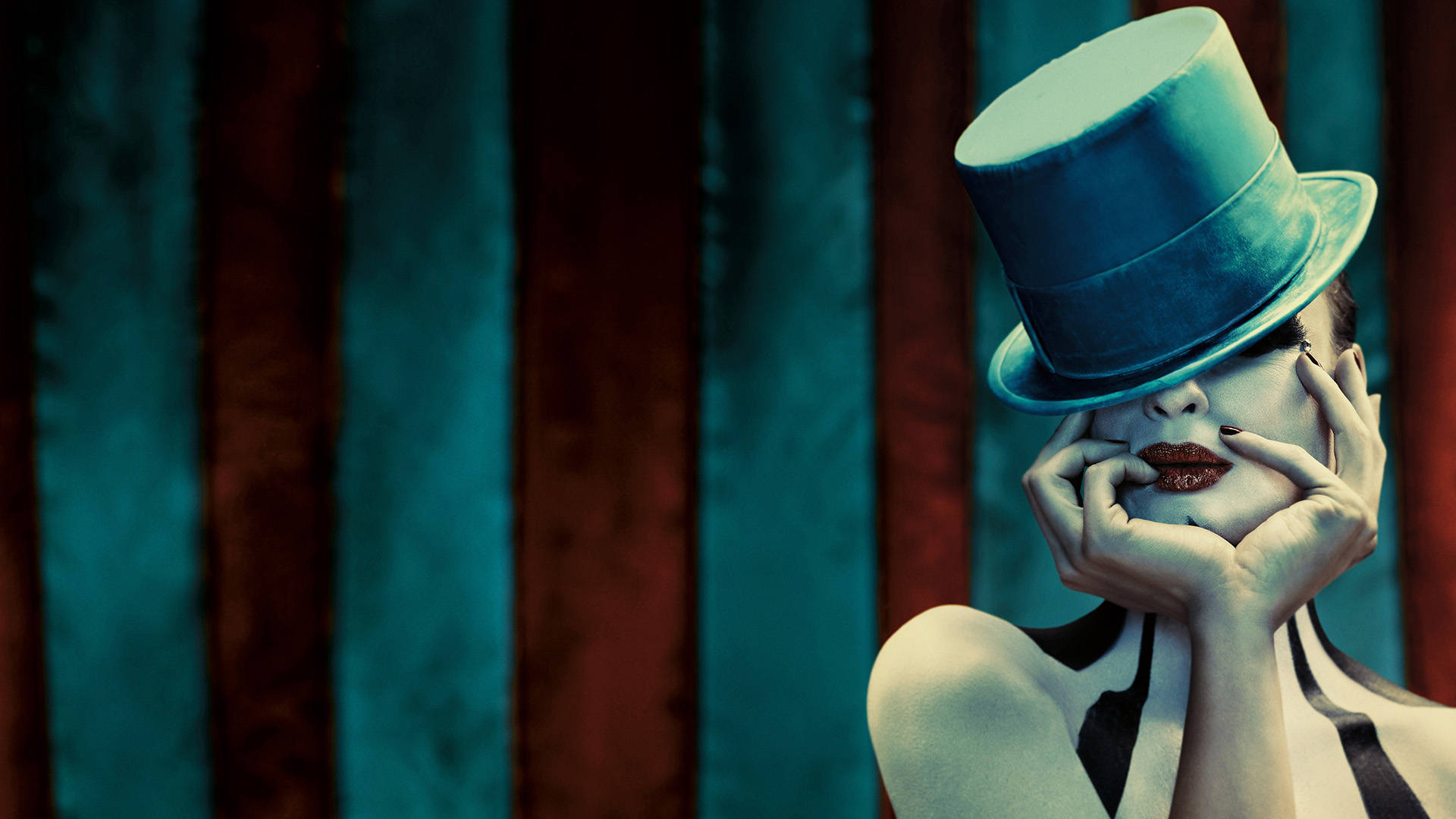 American Horror Story 桌布 壁紙 — 一位戴著青綠色高帽、身穿條紋服裝的女性，雙手捧著臉，背景是條紋窗簾。