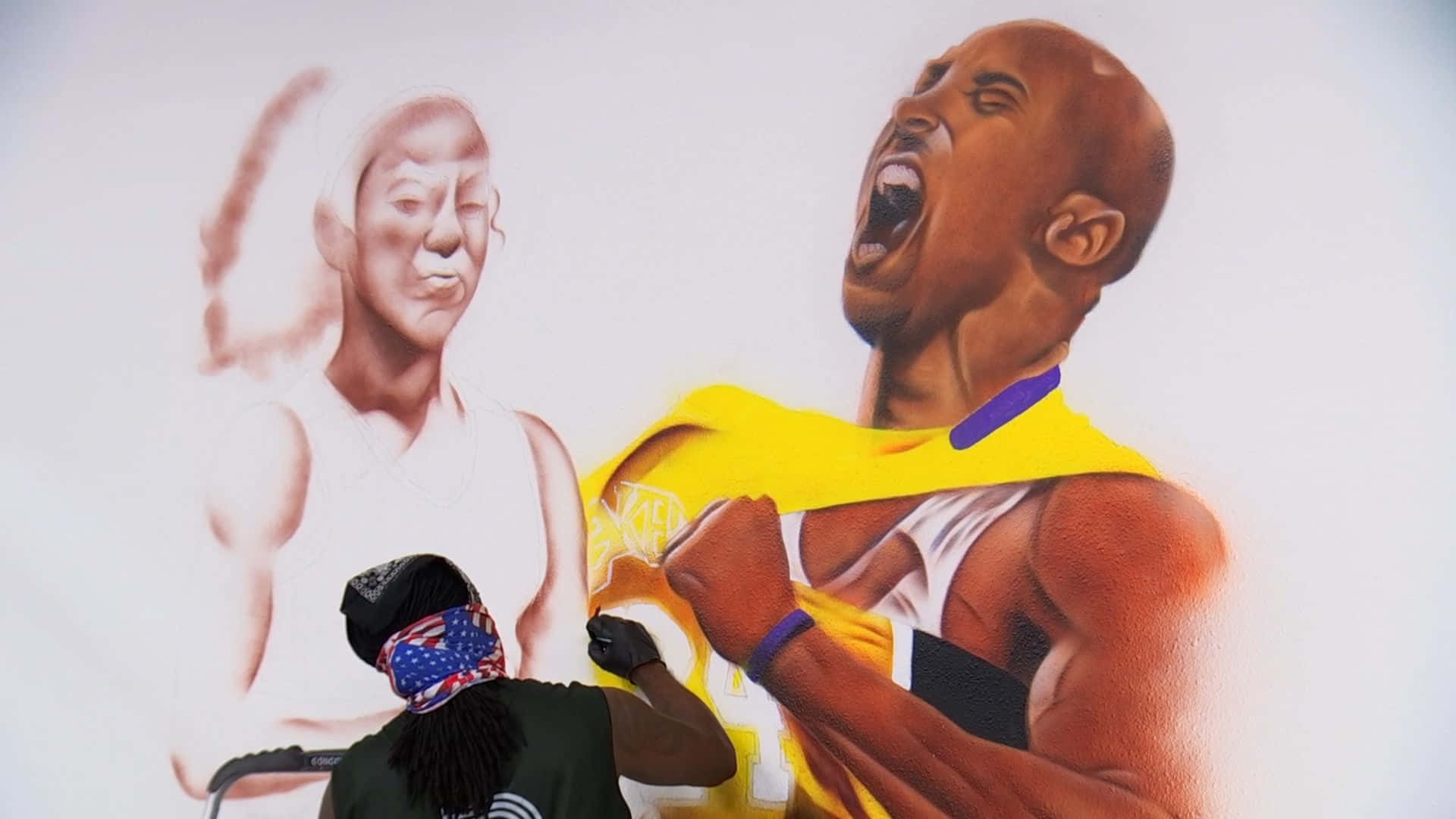 Kobe And Gigi 桌布 壁紙 — 一位戴著頭巾的藝術家正在繪製一幅充滿活力的壁畫，描繪身穿湖人球衣的柯比·布萊恩勝利咆哮，旁邊是褪色的唐納·川普肖像。