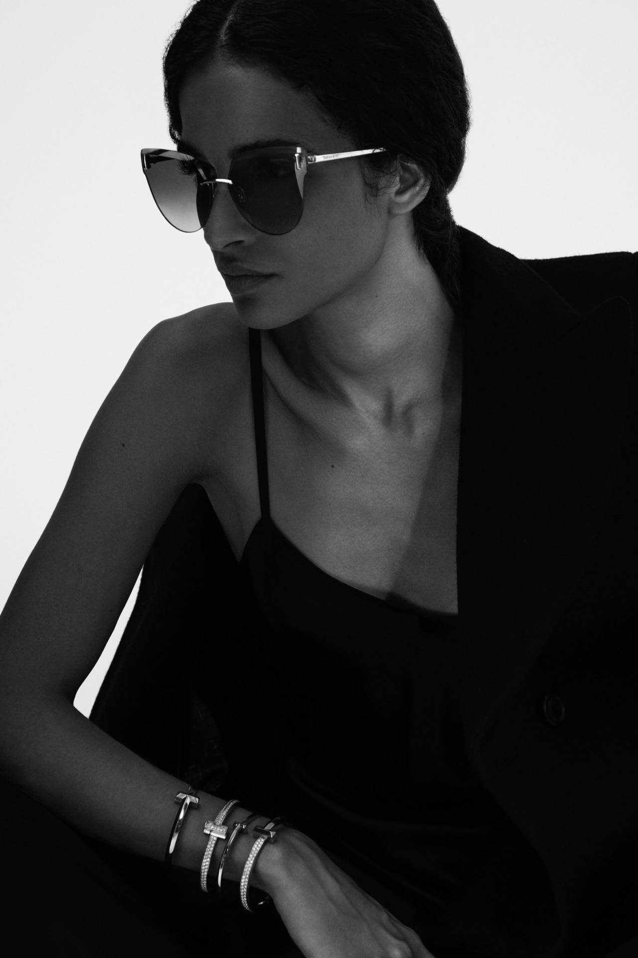 Sunglasses 桌布 壁紙 — 一位戴著黑色太陽眼鏡和西裝外套的優雅女性，在純白背景下散發冷靜自信。