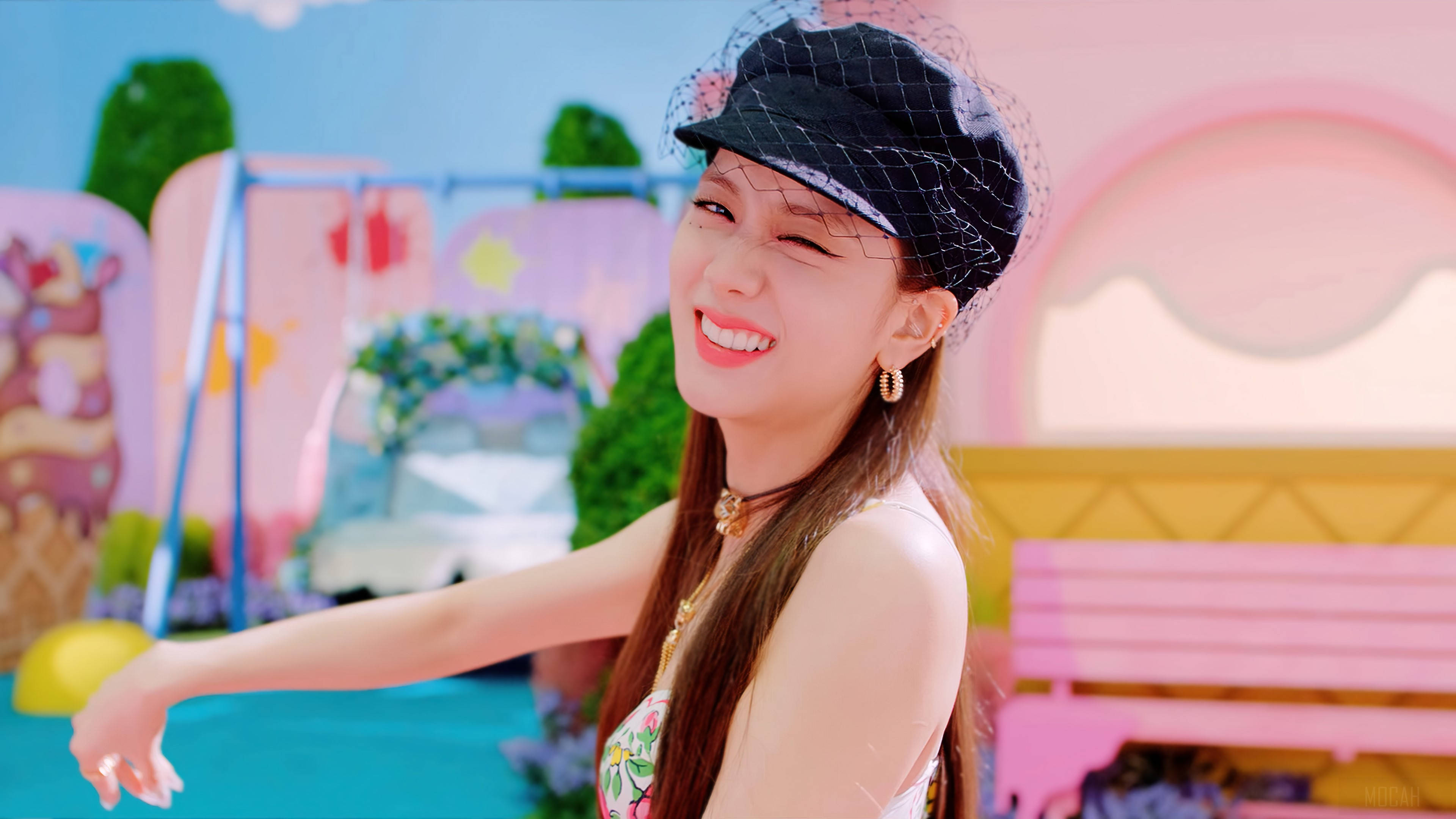 jisoo 可愛 桌布 壁紙 — 一位戴著黑色帽子的快樂女性在粉彩色的夢幻遊樂場環境中燦爛微笑。