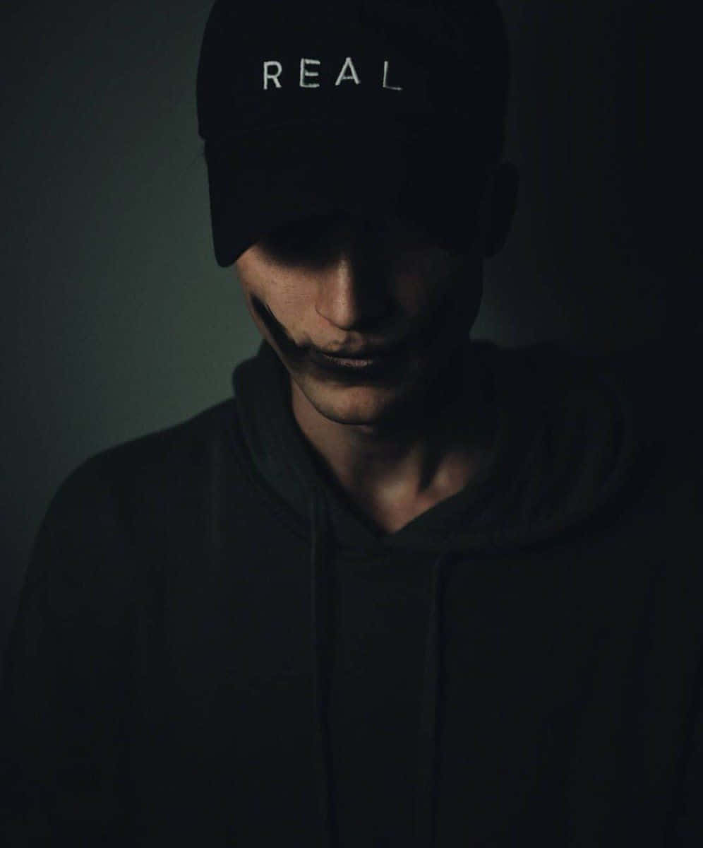一位戴著黑色棒球帽、帽上寫有real字樣的男人 壁紙