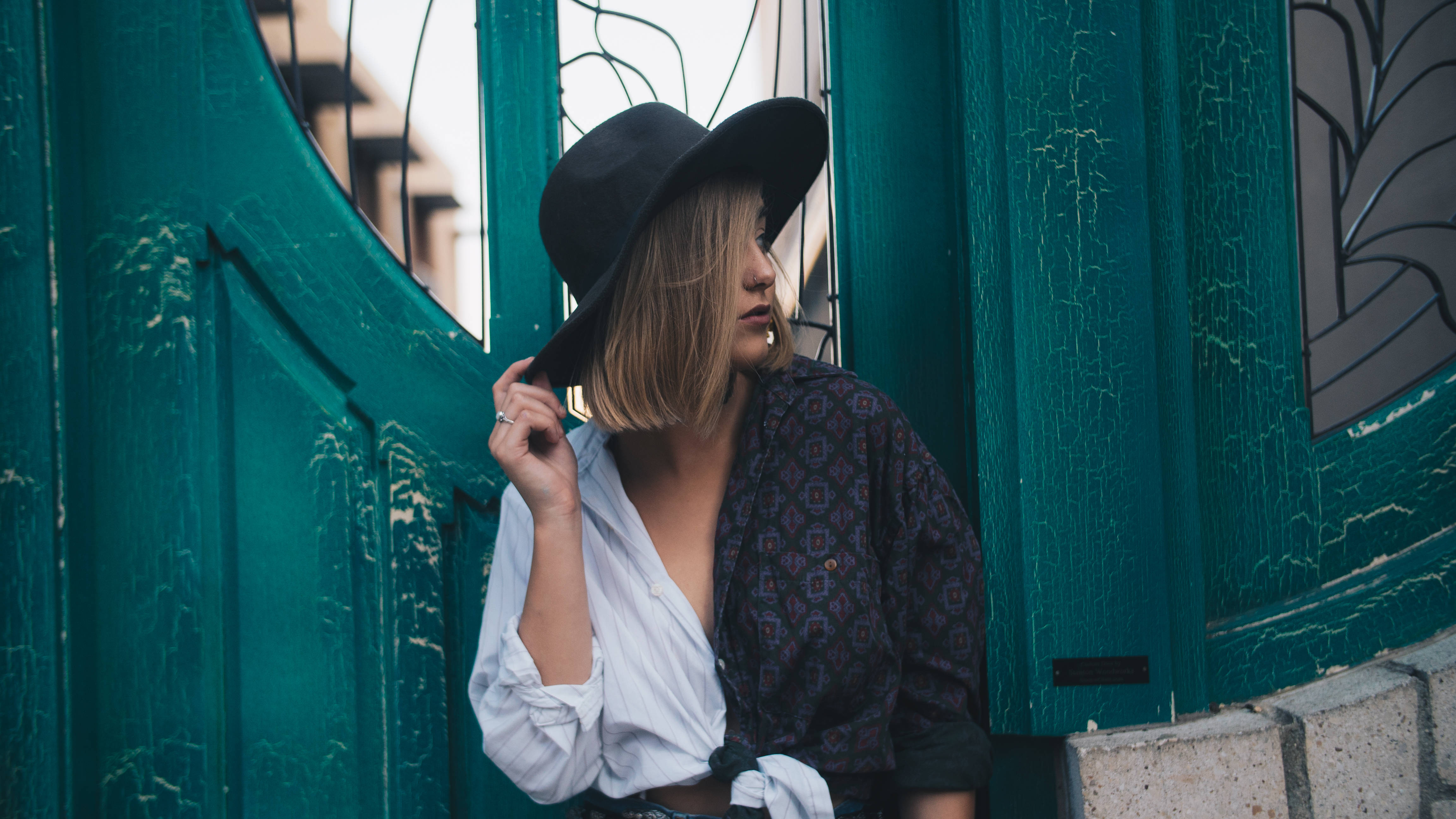 Hipster 桌布 壁紙 — 一位戴黑色帽子的女士靠在一扇褪色的青綠色門上，門上有剝落的油漆和彩色玻璃板。
