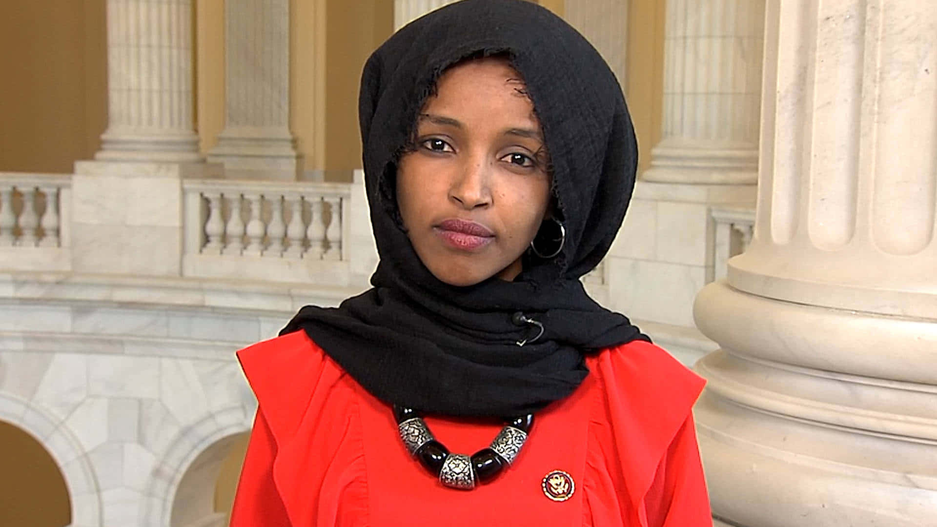Hijab 桌布 壁紙 — 一位戴黑色頭巾、穿紅色襯衫的女性自信地站在宏偉大廳的大理石柱前。