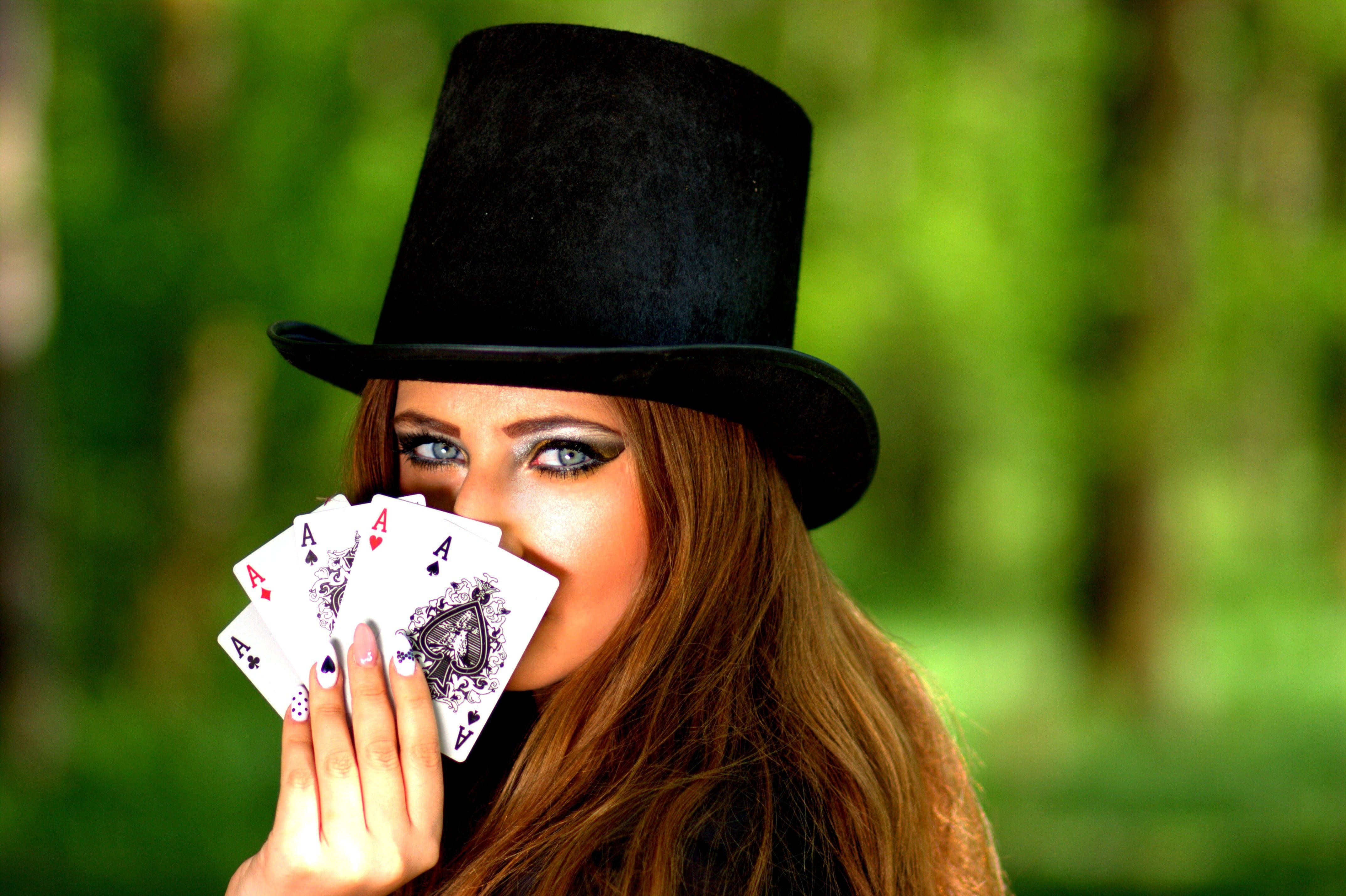 Poker 桌布 壁紙 — 一位戴黑色高帽的女性，在茂密綠色森林背景下，將四張Ace牌舉到臉前。