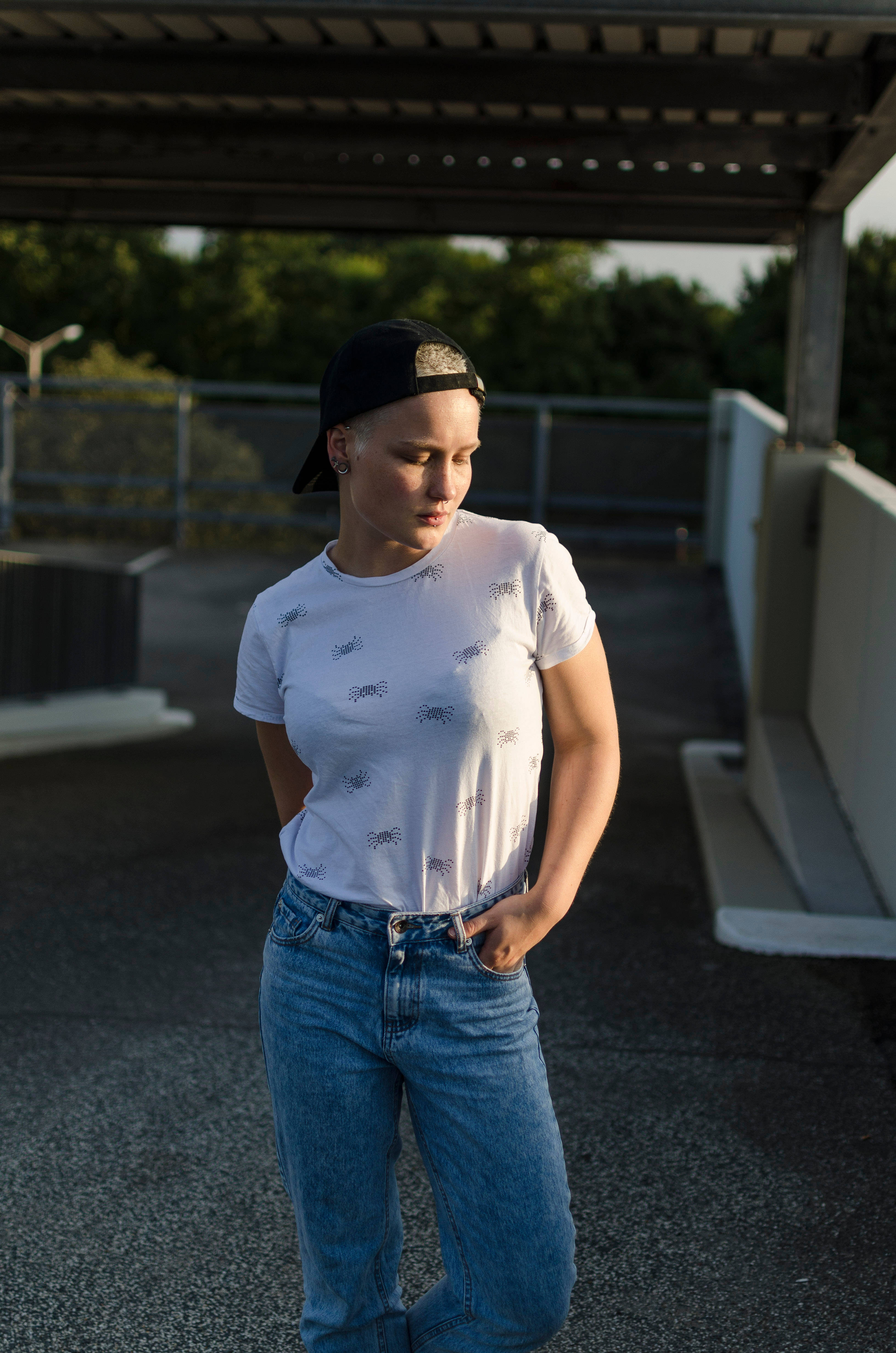 Tomboy 桌布 壁紙 — 一位戴黑色鴨舌帽、身穿蜘蛛圖案T恤的年輕女性，在黃金時刻自信地站在屋頂上。