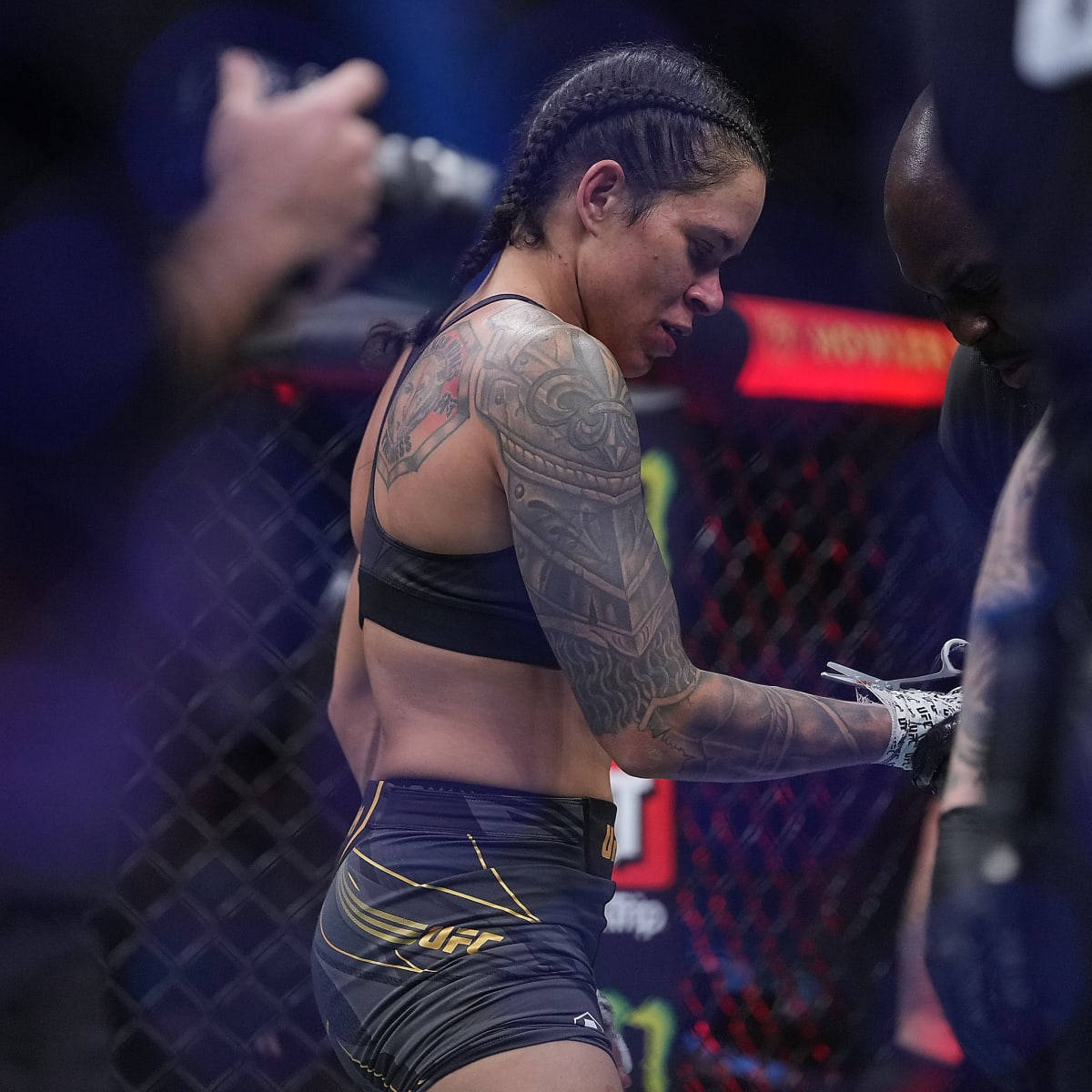 Tattoo 桌布 壁紙 — 一位手臂上有複雜紋身的女MMA拳手站在籠內，比賽後低頭看著。