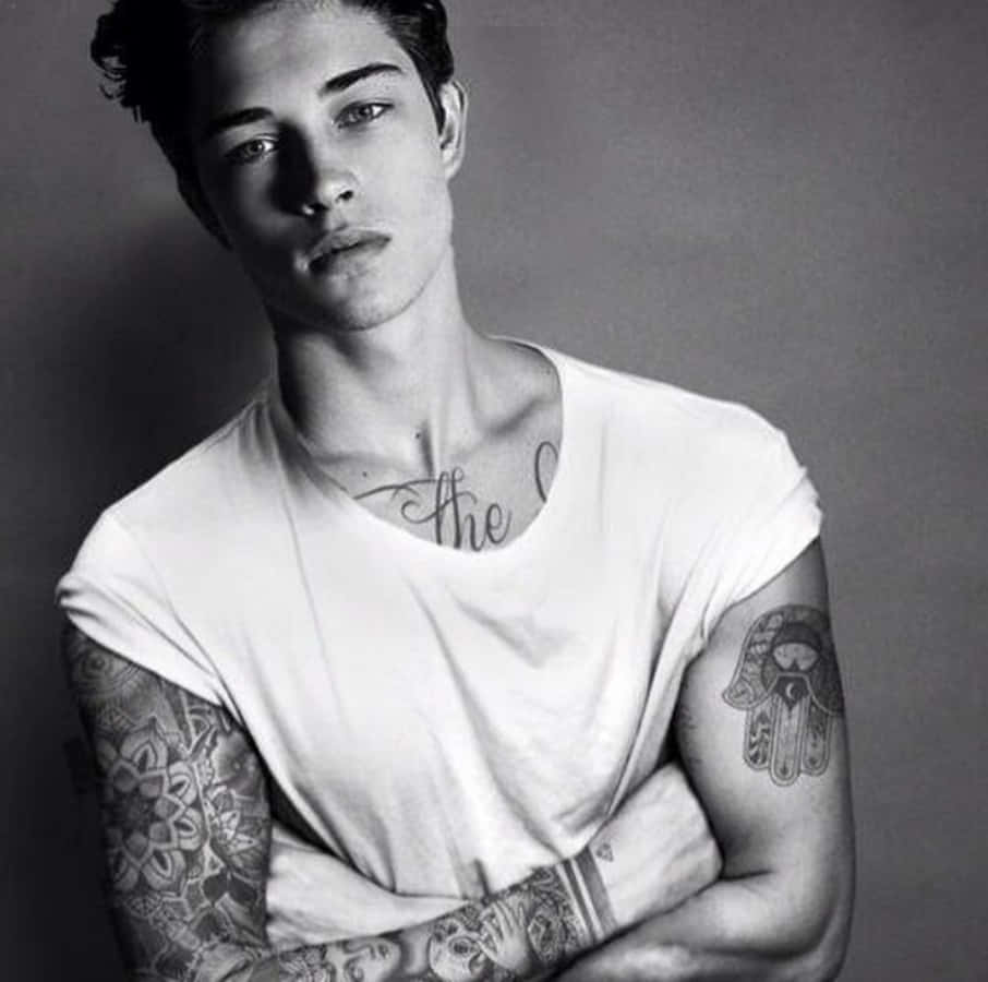 Tattoo Boy 桌布 壁紙 — 一位手臂和頸部有刺青的年輕男子在黑白工作室肖像中直視鏡頭。