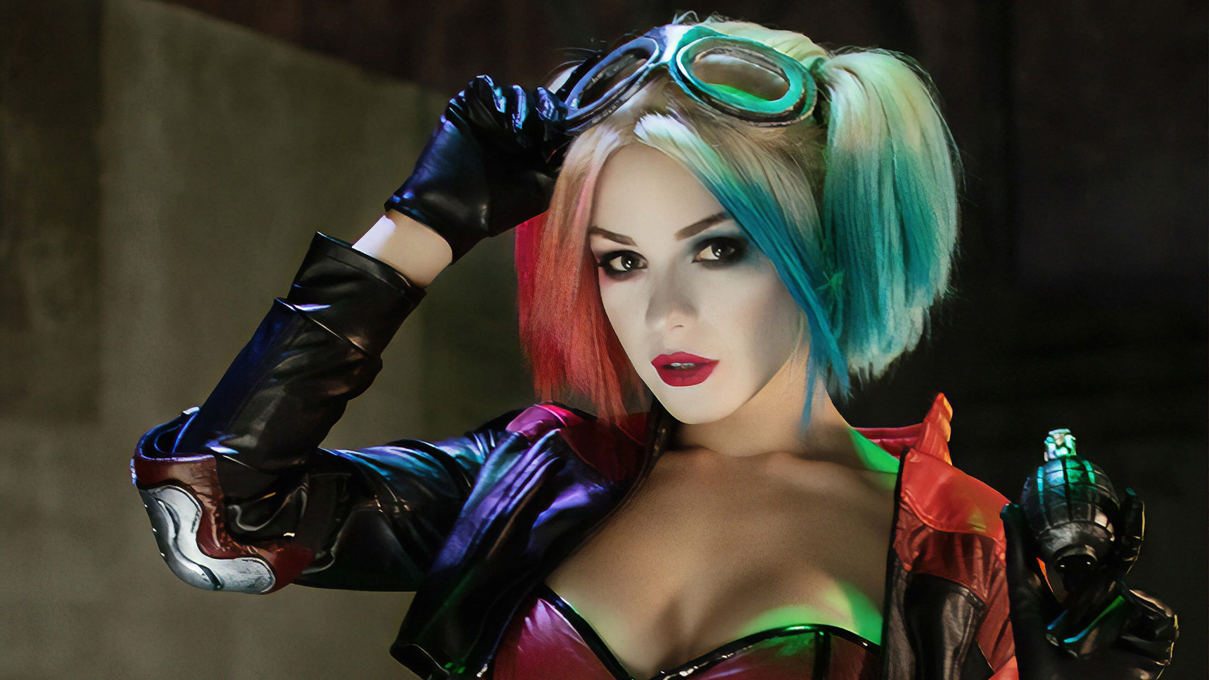 Harley Quinn Cosplay 桌布 壁紙 — 一位扮演哈莉·奎茵的角色扮演者，身穿色彩繽紛的服裝，戴著護目鏡並手持手榴彈，在昏暗的城市背景下自信地擺出姿勢。