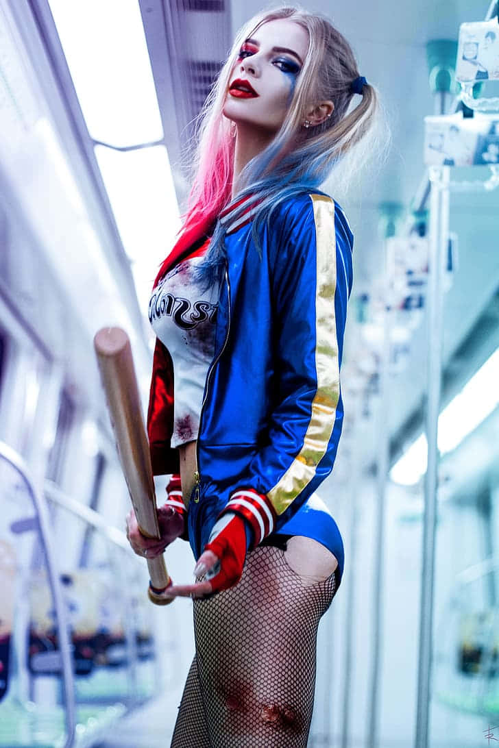 Harley Quinn Cosplay 桌布 壁紙 — 一位扮演小丑女哈莉·奎茵的角色扮演者在醫院走廊自信地擺姿勢，手持棒球棍，擁有鮮豔的粉藍色頭髮和大膽的妝容。
