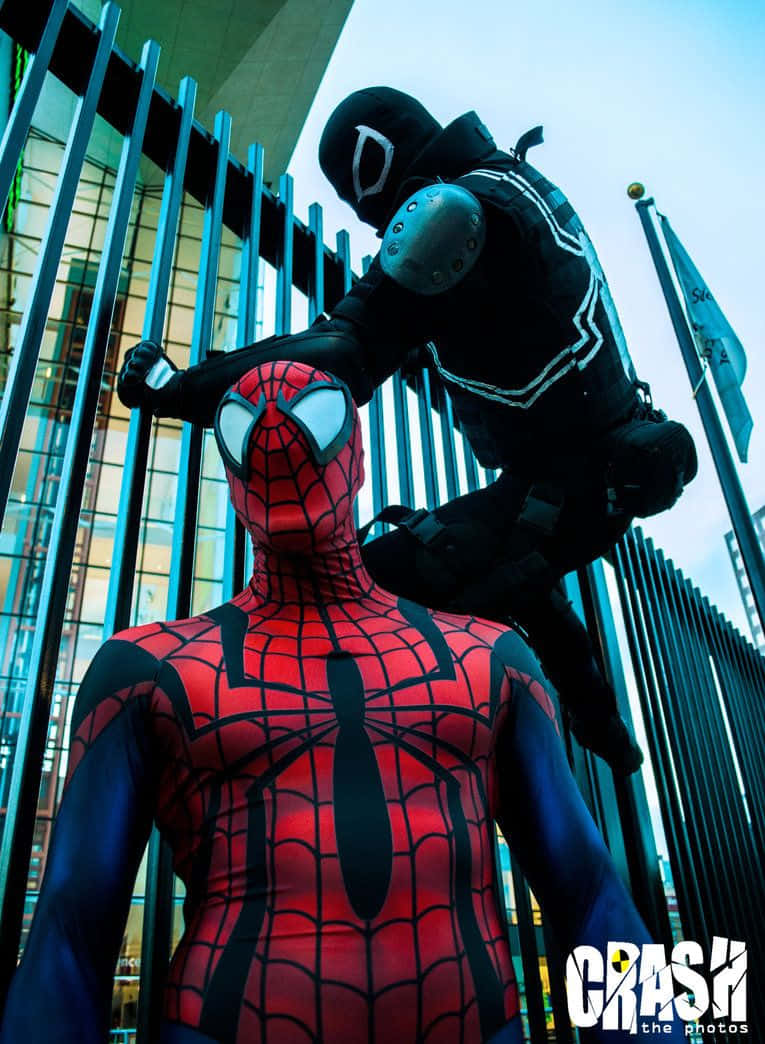 Flash Thompson 桌布 壁紙 — 一位扮演蜘蛛人的cosplayer與另一位扮演猛毒的cosplayer以戲劇性的低角度城市姿勢對峙。