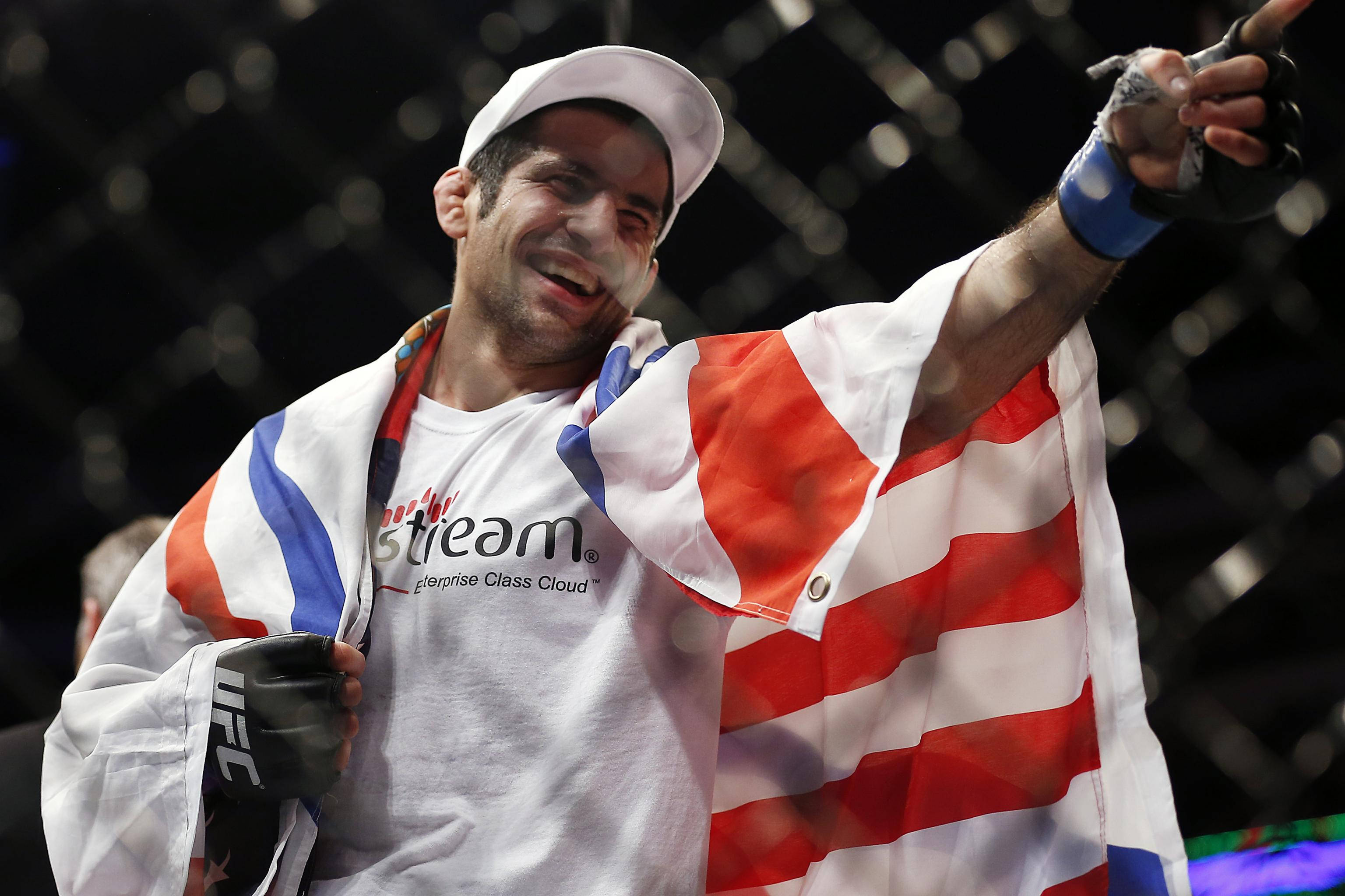 UFC 桌布 壁紙 — 一位披著美國國旗的UFC拳手，在八角籠內指向人群，滿臉喜悅。