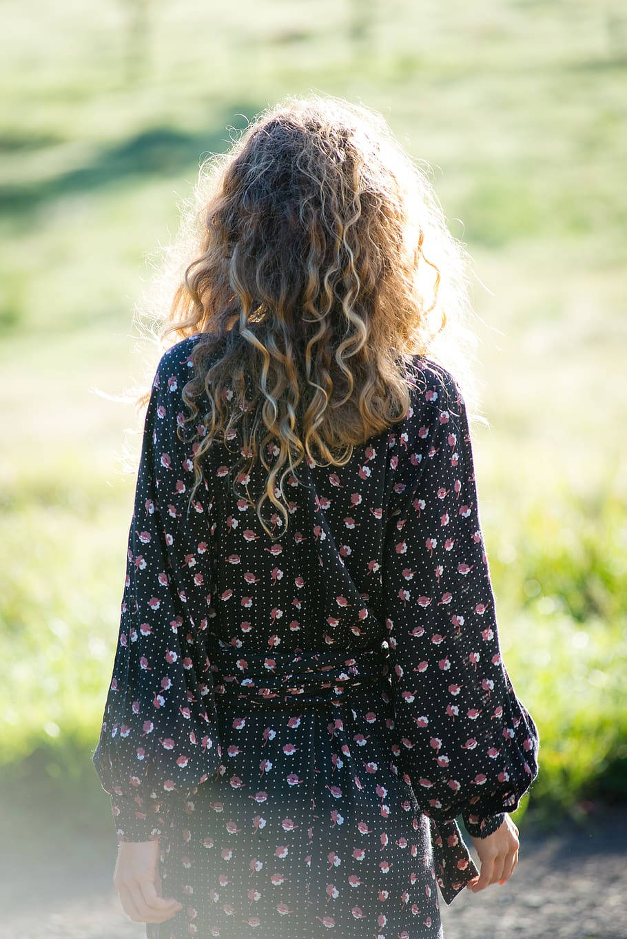 Polka Dot 桌布 壁紙 — 一位捲髮女子穿著碎花裙，在陽光照耀的草地上走遠。