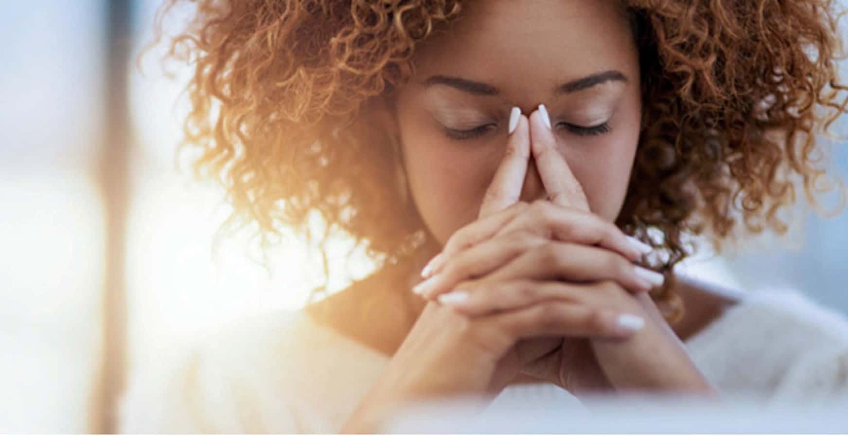 Emotional 桌布 壁紙 — 一位捲髮女性在溫暖的金色陽光下合十祈禱。