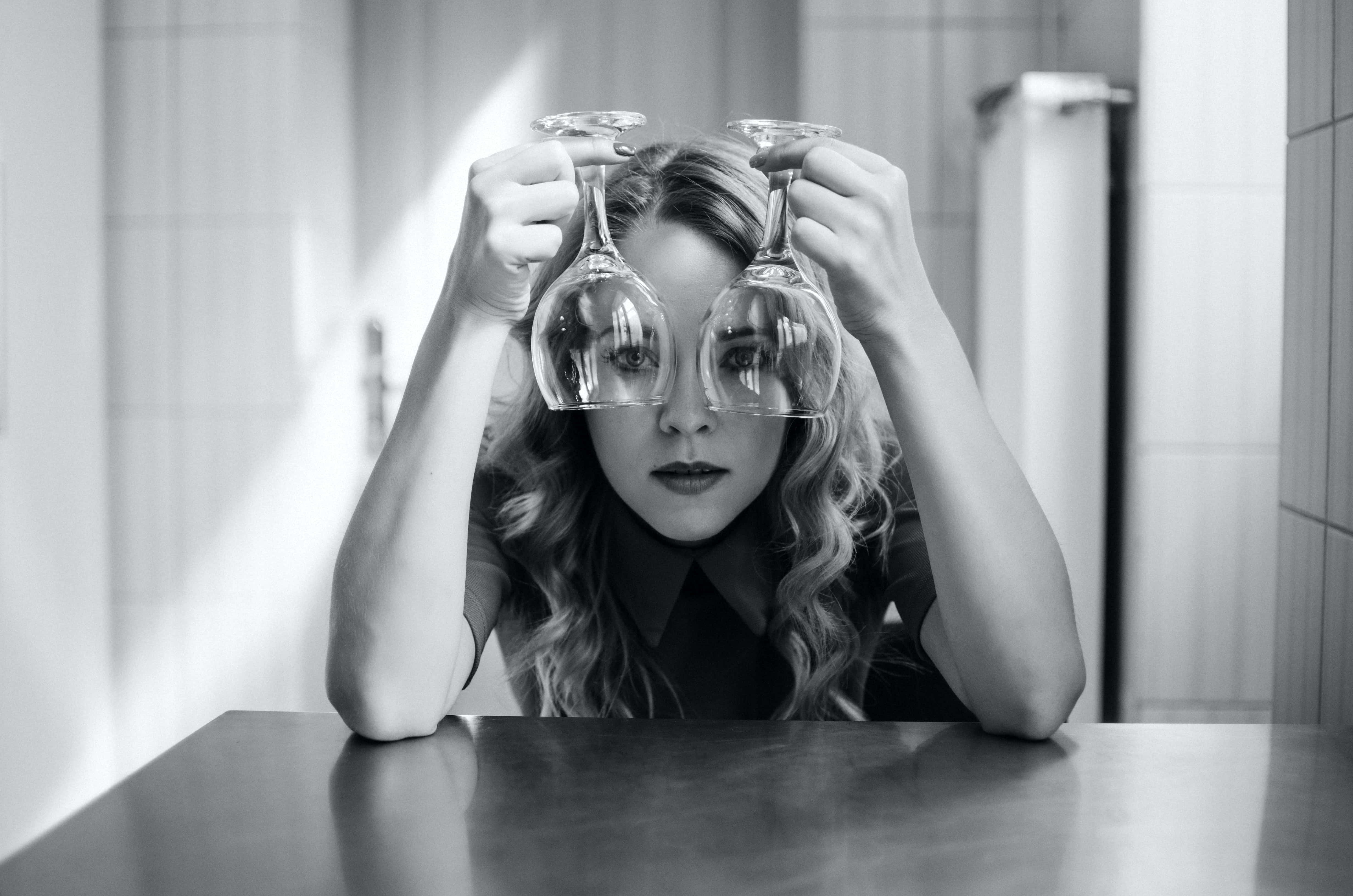Aesthetic Black And White 桌布 壁紙 — 一位捲髮女性在黑白浴室中將兩個酒杯放在眼前。