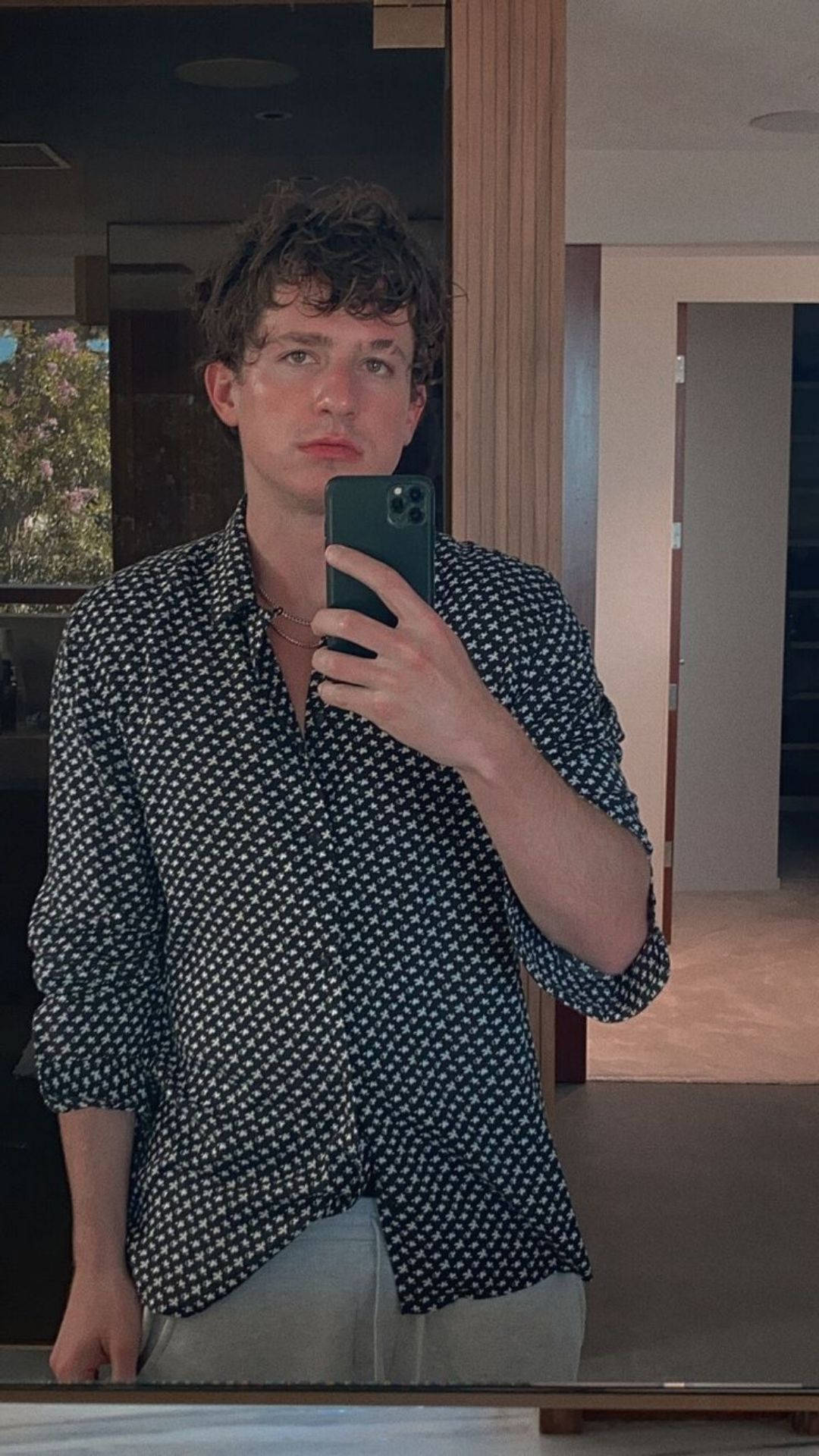 Charlie Puth 桌布 壁紙 — 一位捲髮年輕男子在室內穿著圖案襯衫，利用窗戶的自然光拍攝鏡子自拍。