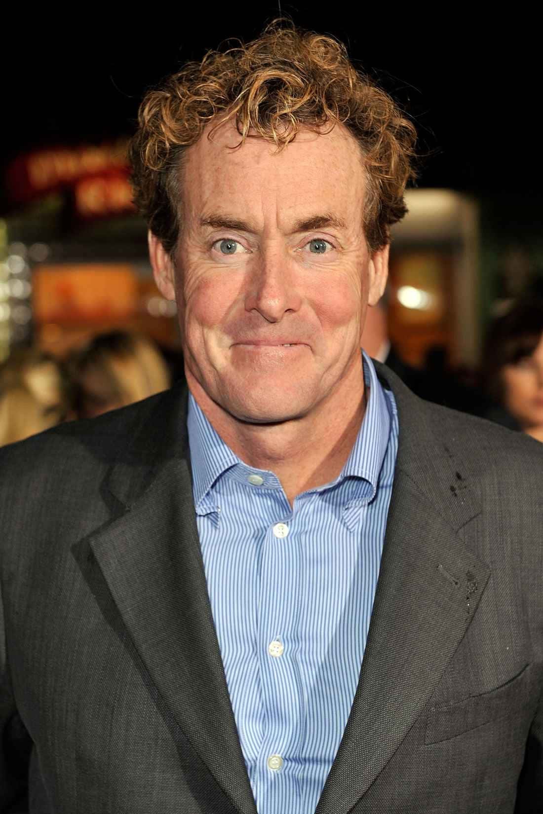 John C. Mcginley 桌布 壁紙 — 一位捲髮男士在夜間活動中穿著灰色西裝和藍色條紋襯衫的特寫肖像。